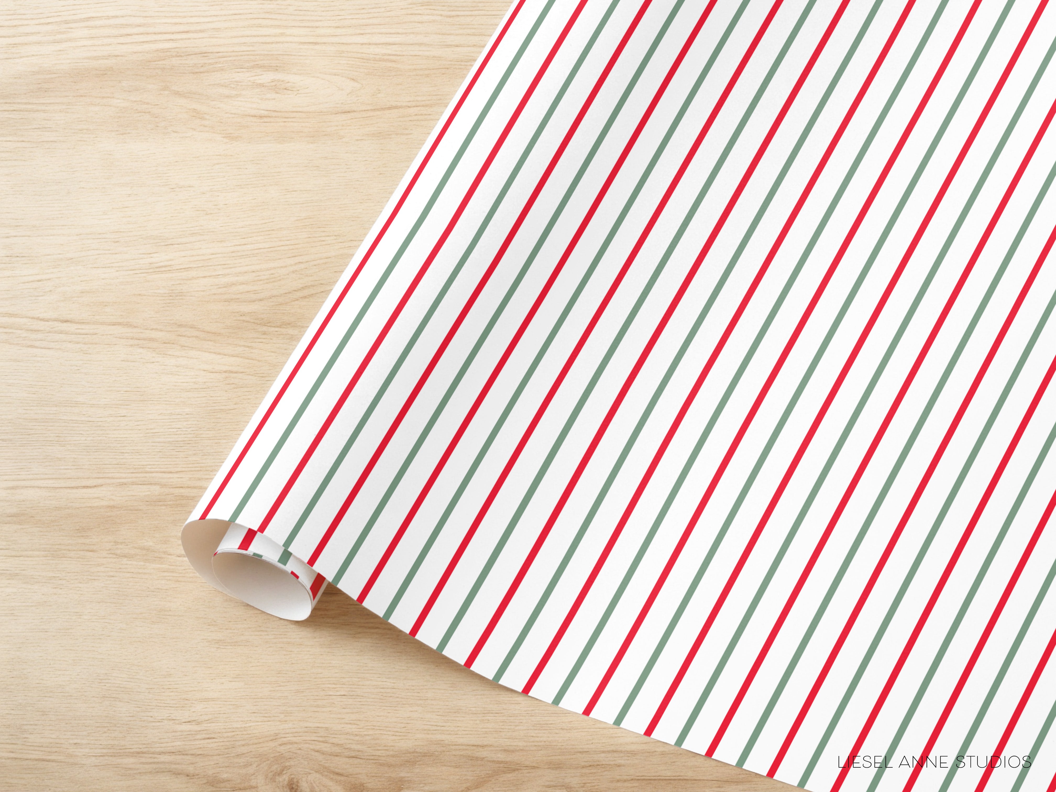 A roll of wrapping paper with red and green stripes is placed on a wooden surface.