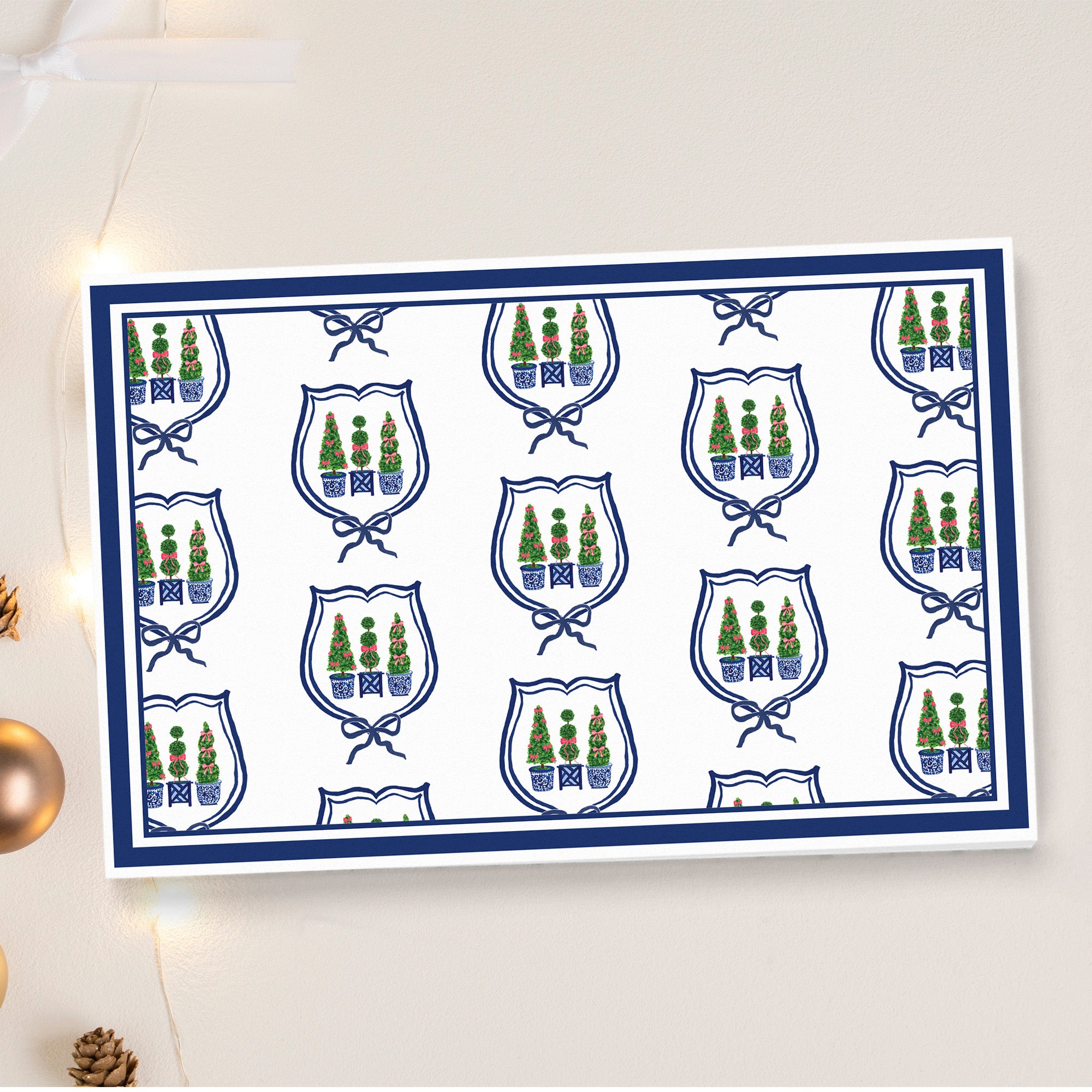 a repeating pattern of blue and white shields with green trees and blue bows, arranged in a grid-like layout.