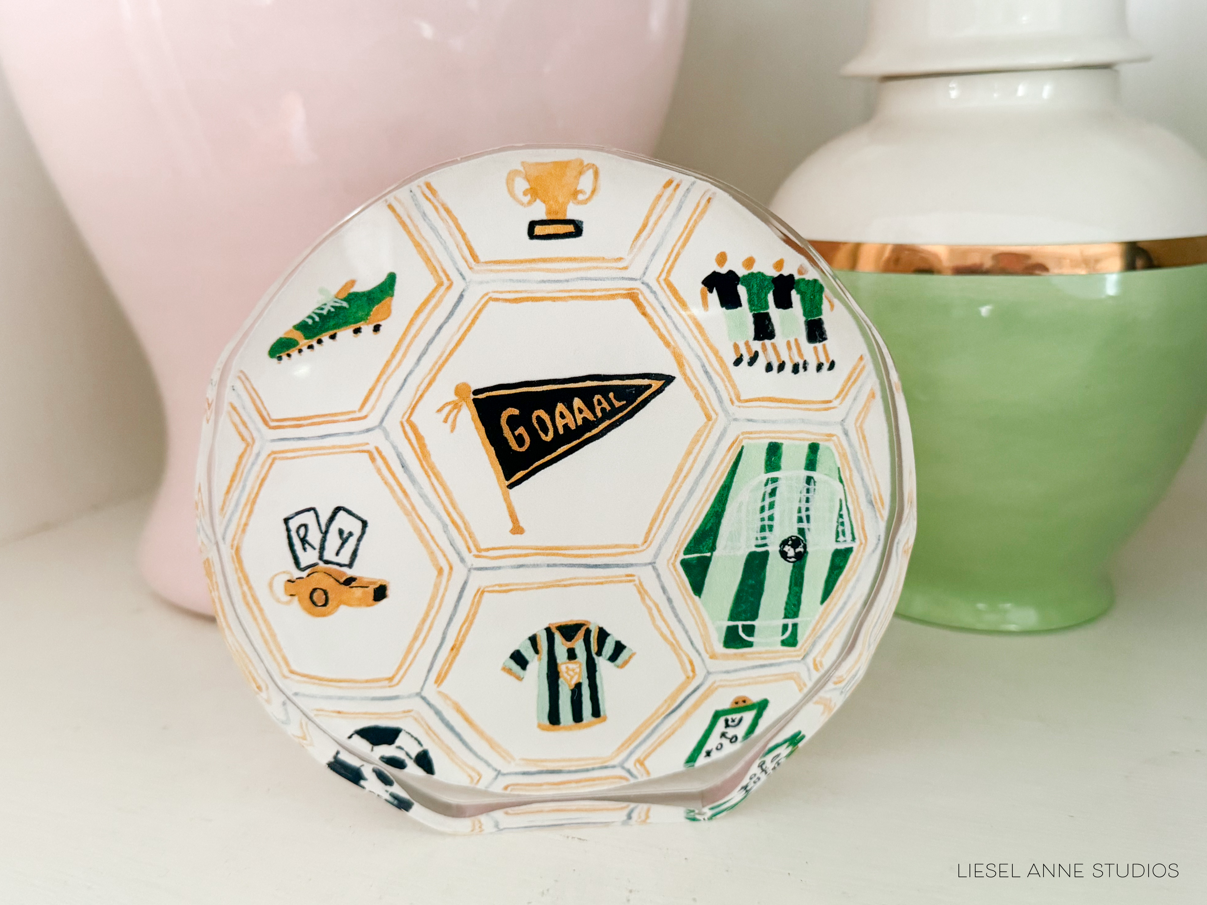 A soccer-themed plate with various soccer-related icons and text, including a soccer ball, trophy, players, and a flag.