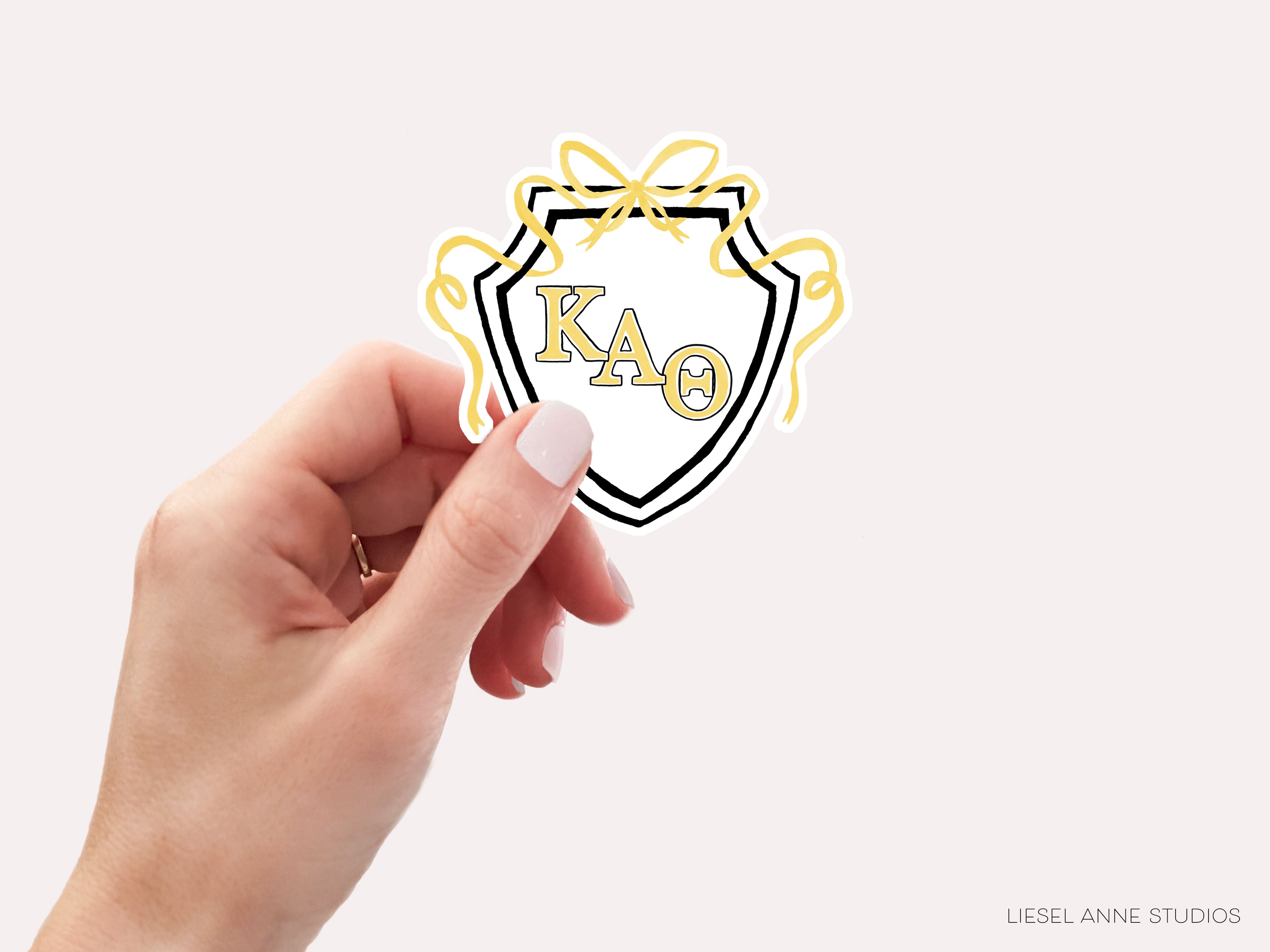 a hand holding a sticker with the letter k a d