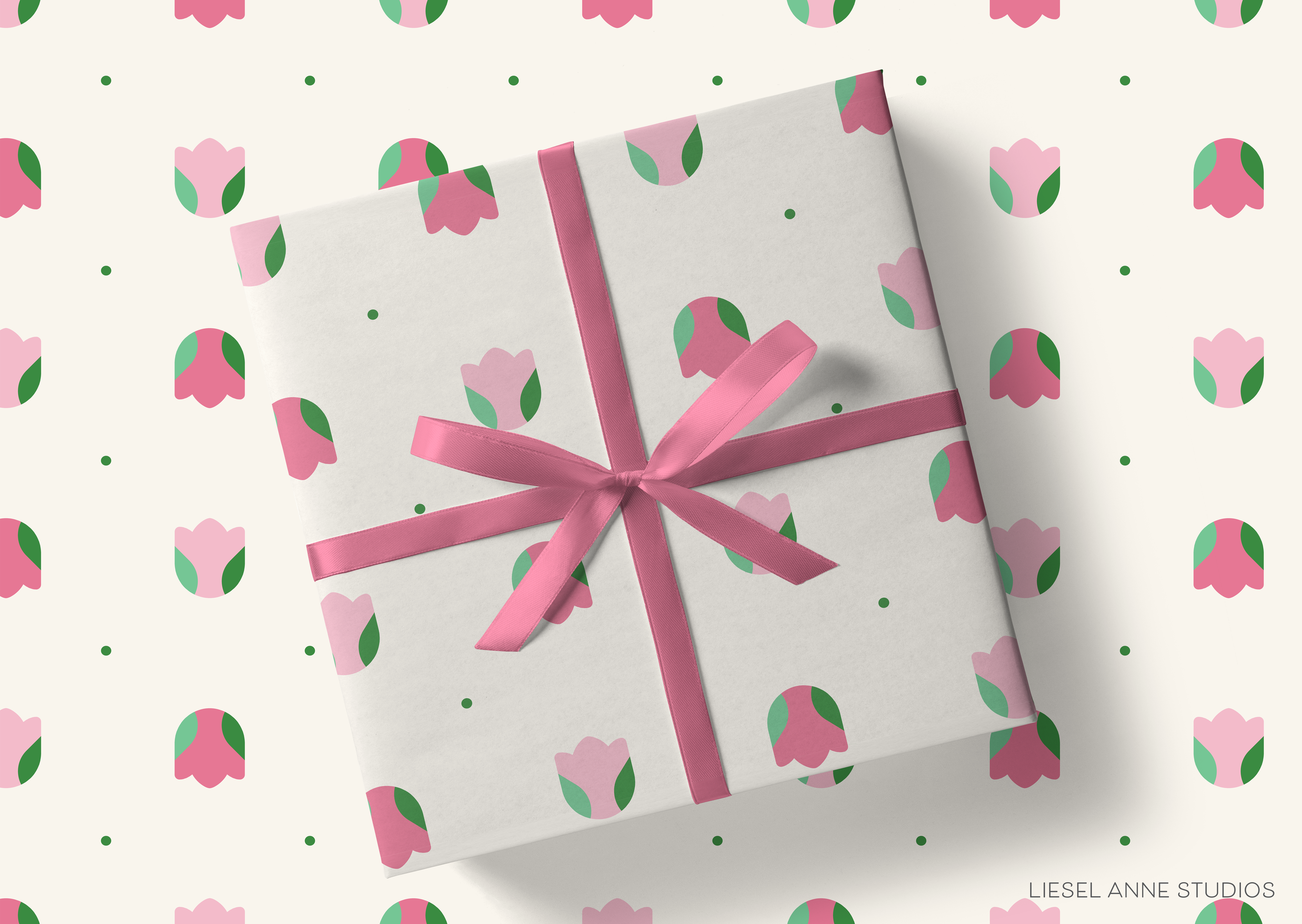 a gift box with a pink ribbon and a repeating pattern of pink and green flowers on the wrapping paper.