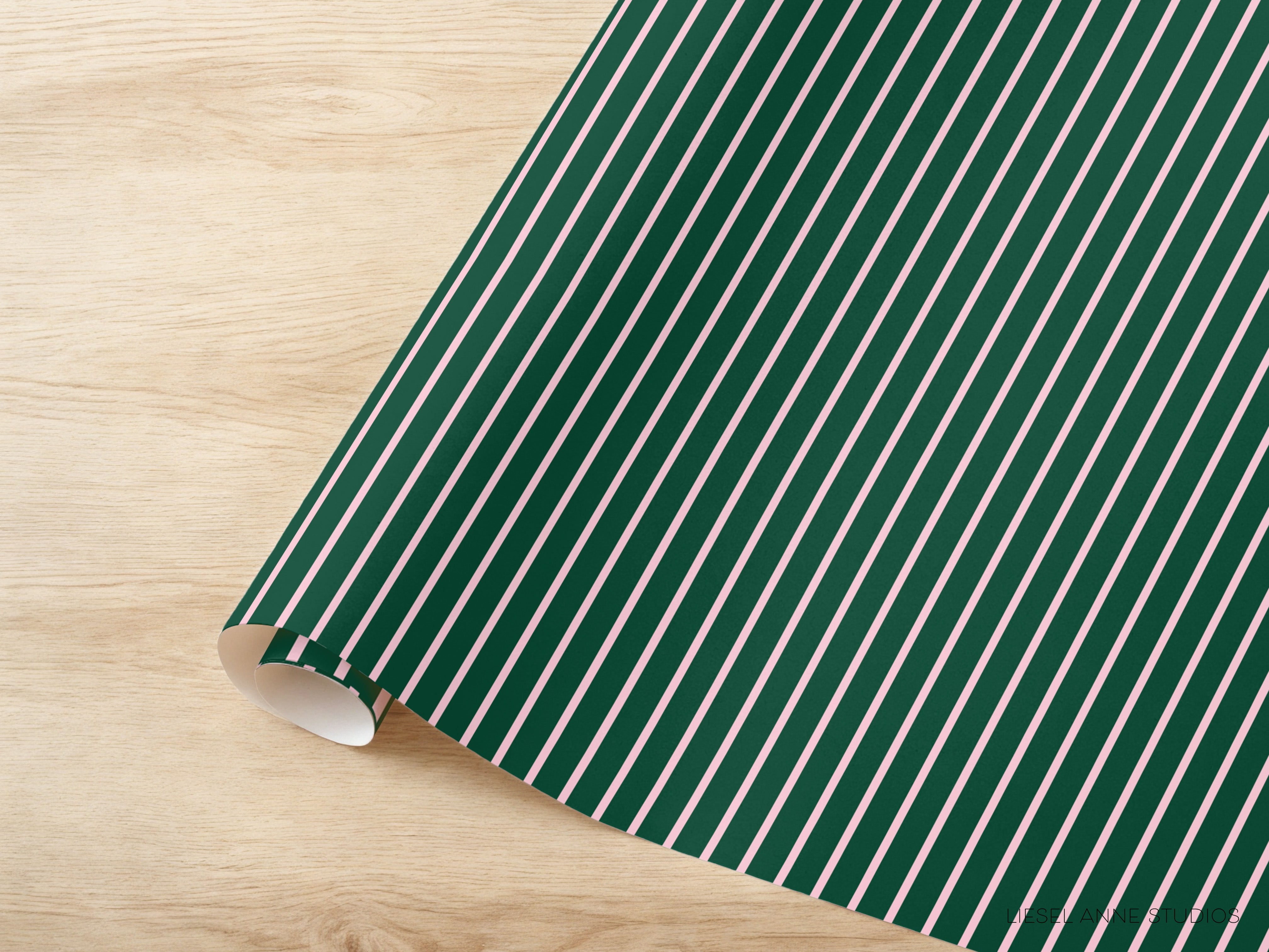A roll of green and white striped wrapping paper is placed on a wooden surface.