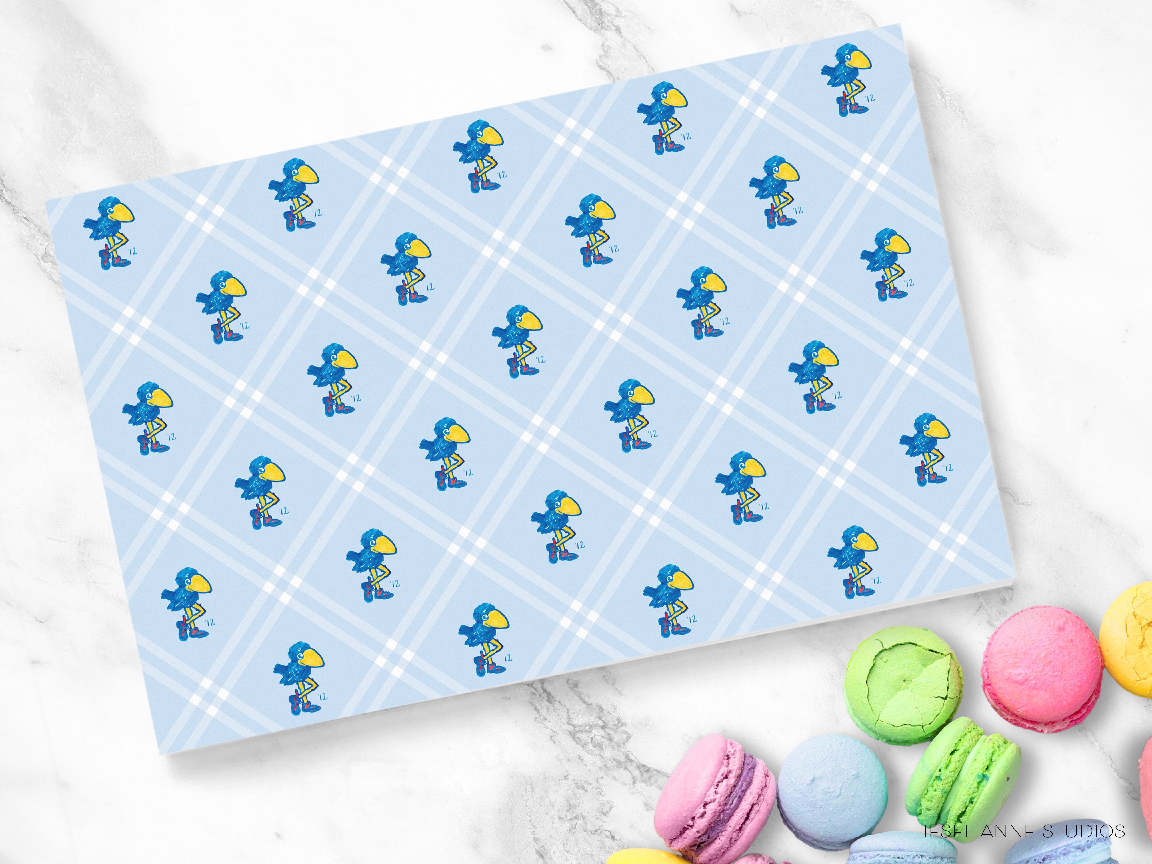 a blue and white checkered pattern with small blue birds on it, along with a variety of colorful macarons arranged on a marble surface.