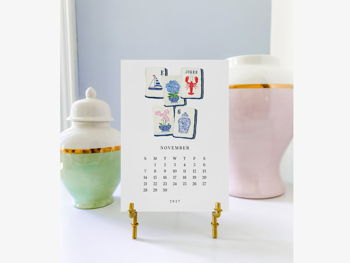 November mahjong page of the Happy Hobbies 2027 watercolor desk calendar on a gold easel, a gift for mahjong lovers
