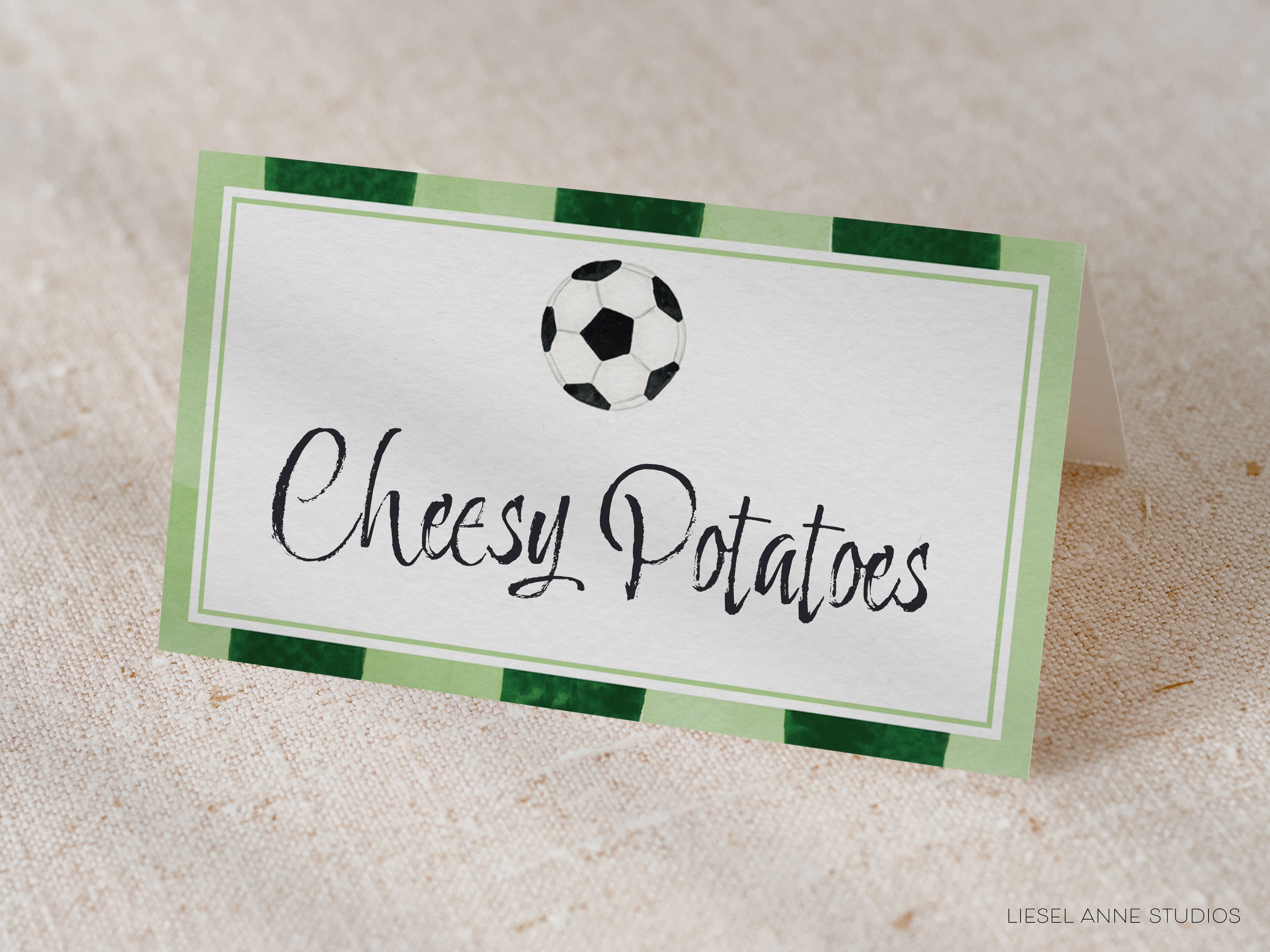 A green and white rectangular card with the text "Cheesy Potatoes" written on it, along with a soccer ball graphic.