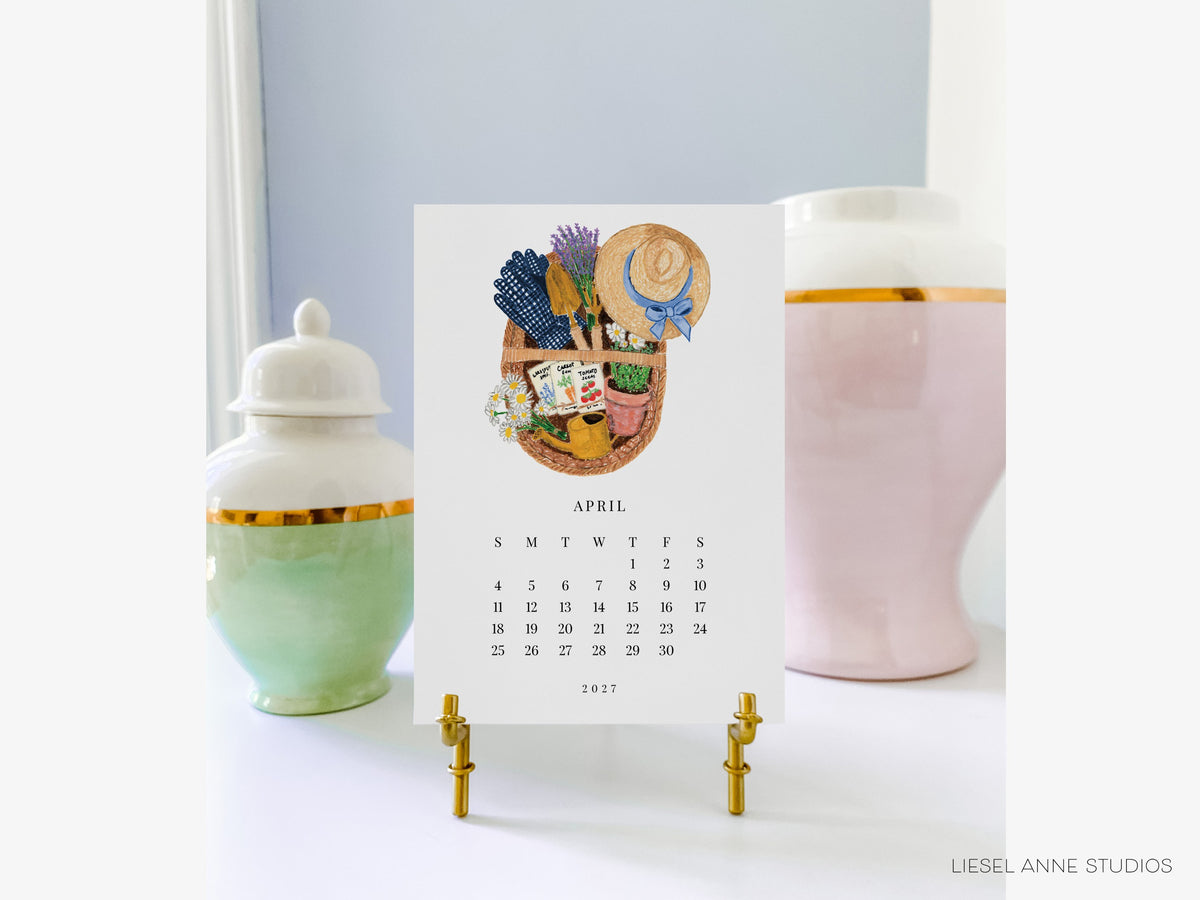 April gardening page of the Happy Hobbies 2027 desk calendar on a gold easel, a gift for gardeners