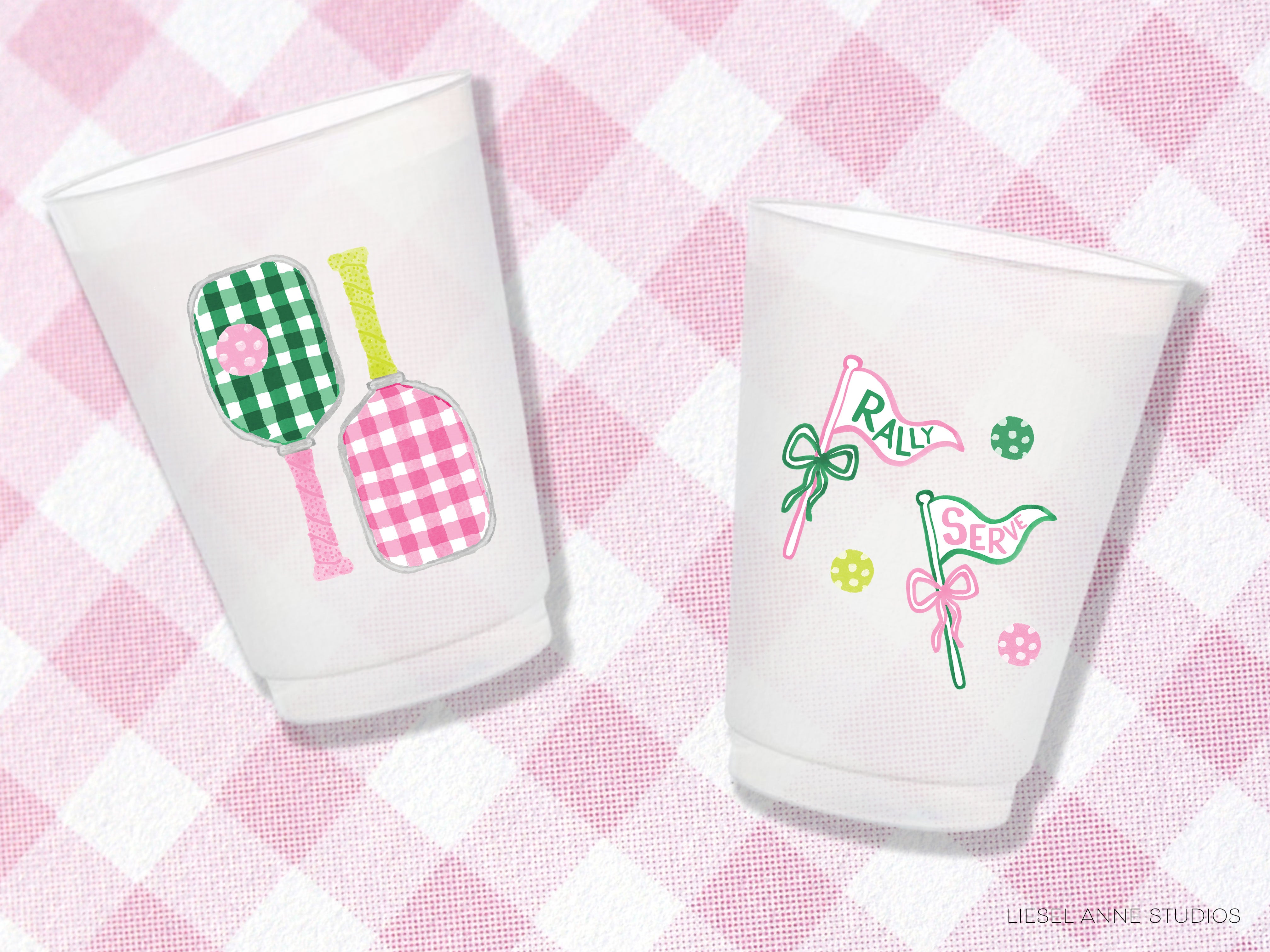 two white cups with pink and green designs on them, placed on a pink and white checkered background.