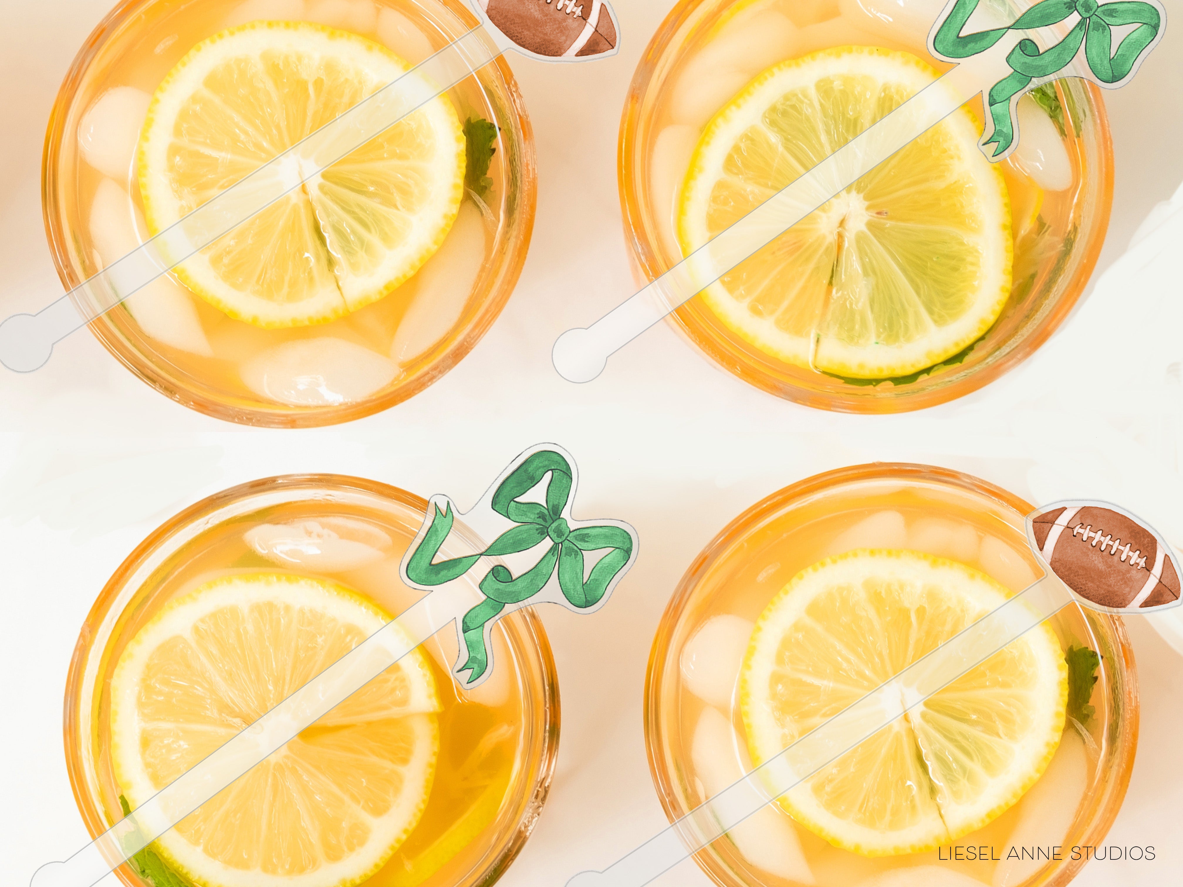 four glasses filled with a yellow liquid, each containing a slice of lemon and a green ribbon.