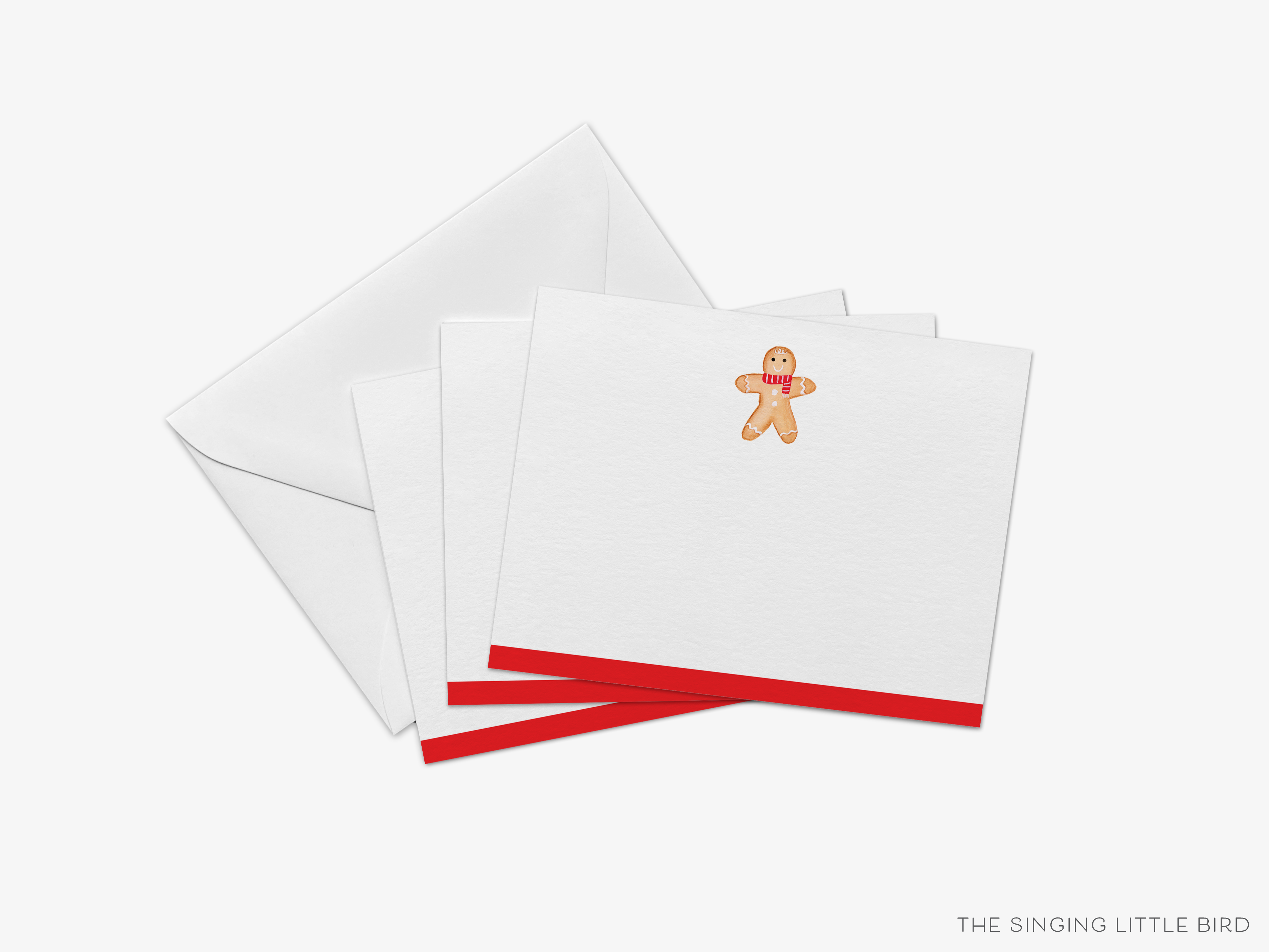 a set of white greeting cards with red borders, featuring an illustration of a gingerbread man on one of the cards.