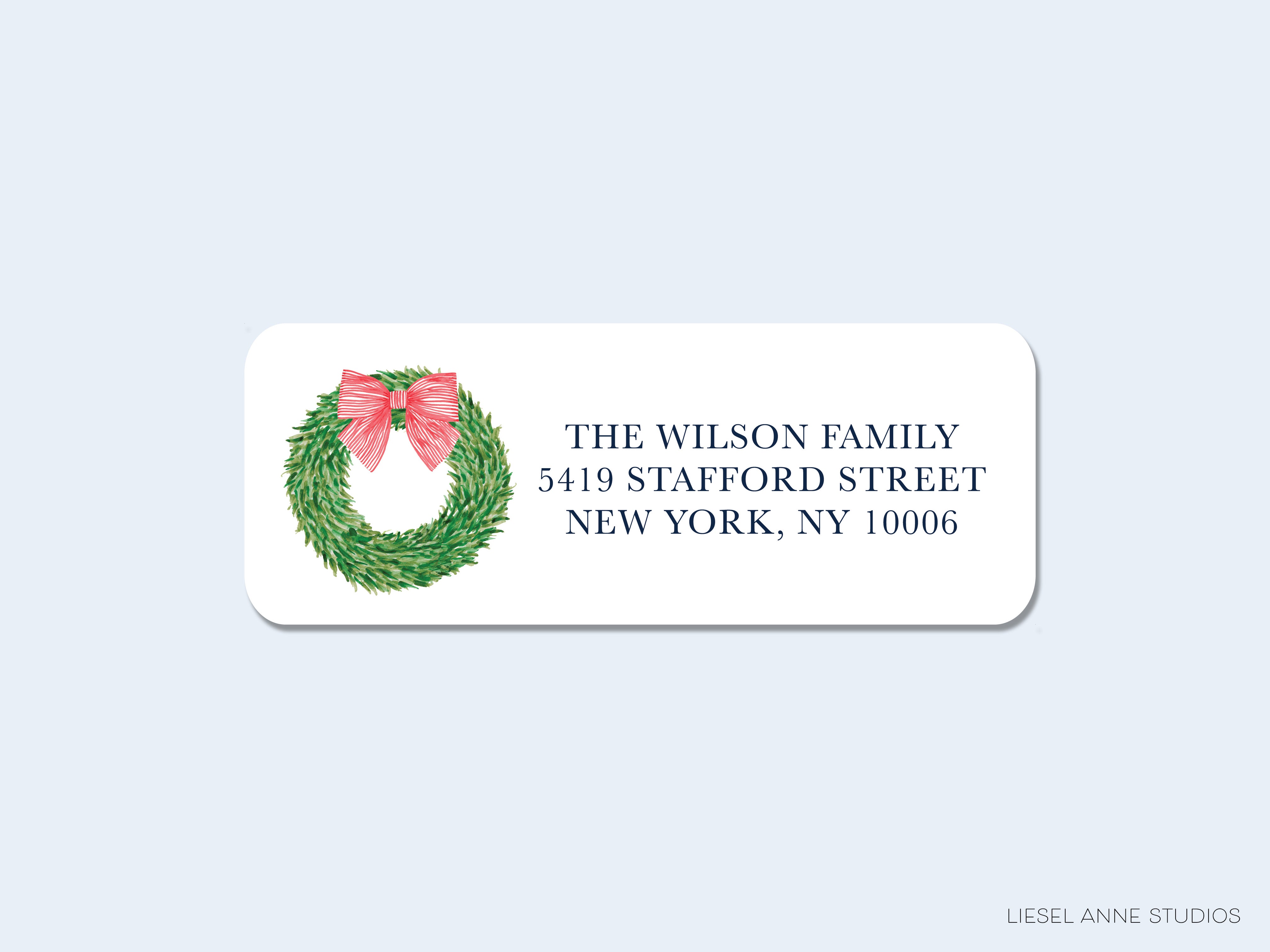 A white rectangular address label with a wreath and a pink bow on it, along with the address "The Wilson Family 541 Station Street New York, NY 10006".