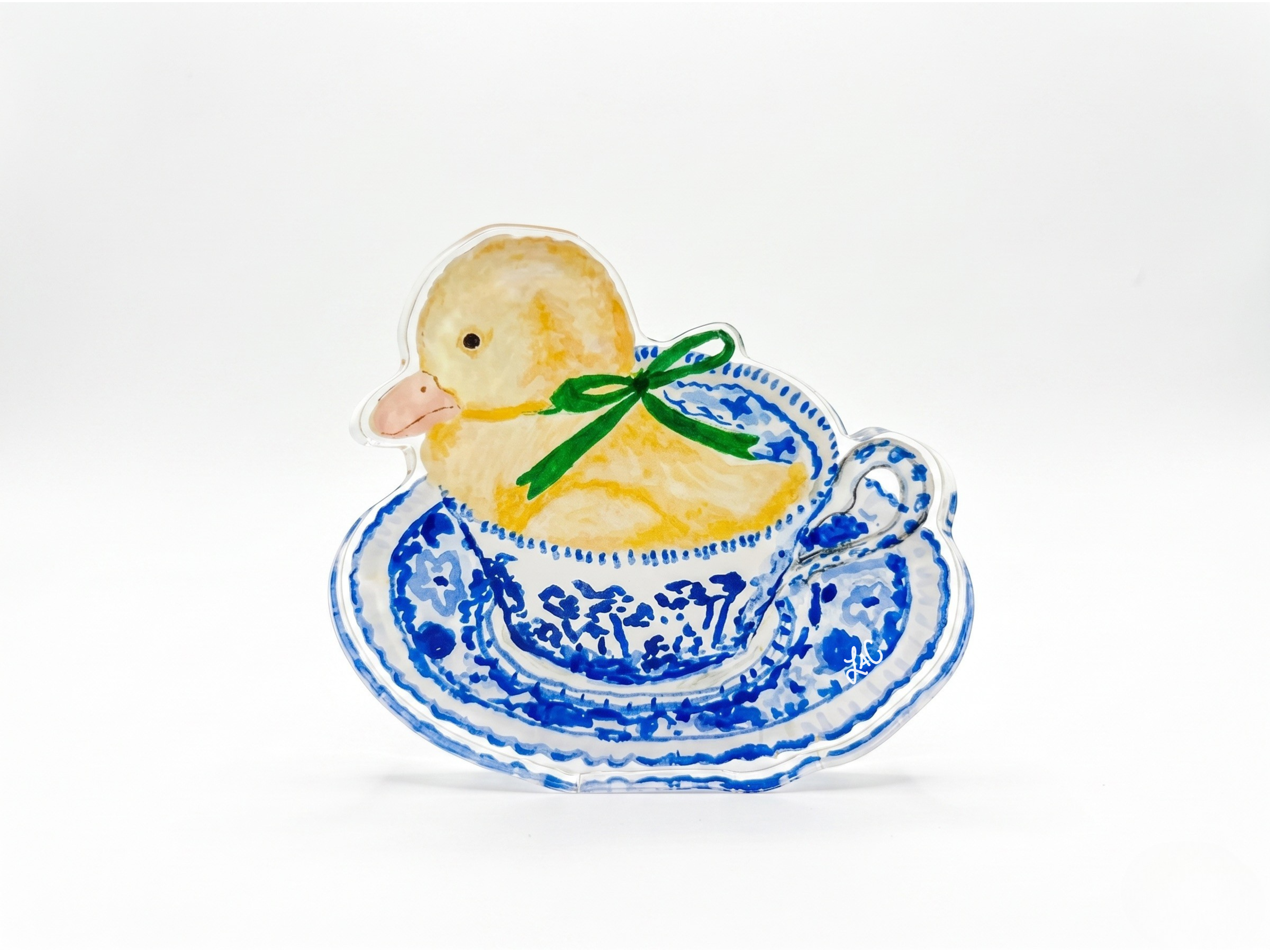 A ceramic teacup with a yellow duck sitting inside it, decorated with blue floral patterns.