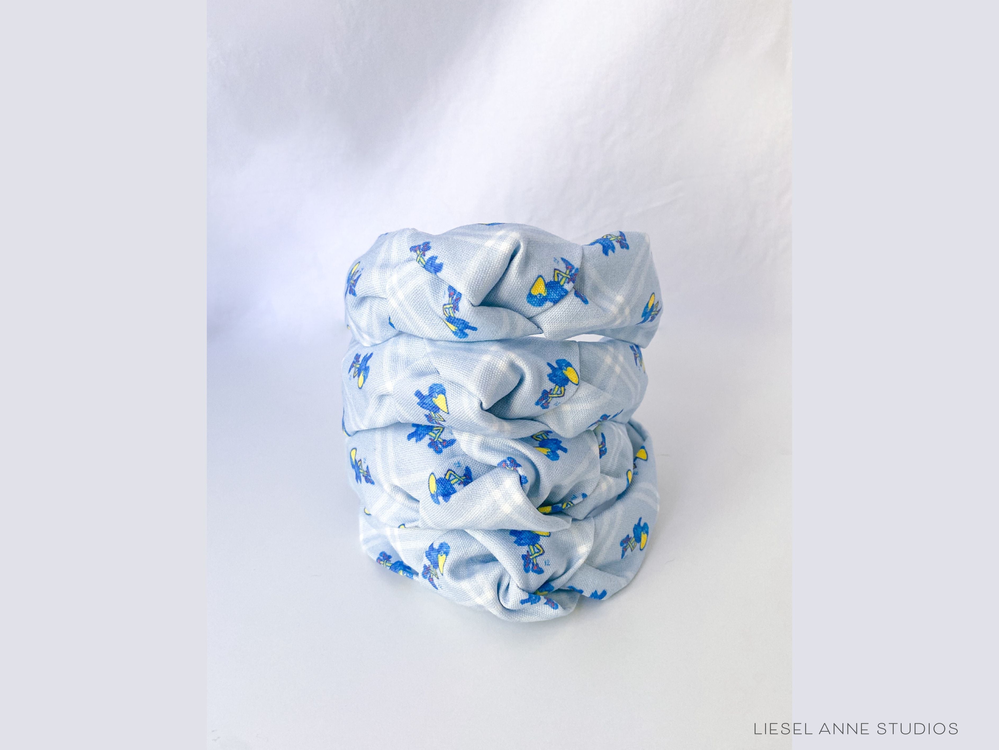 1912 Jayhawk Officially Licensed Light Blue Diamond Headband-These fabric headbands make unique one-of-a-kind gifts as each one is slightly different. They are cut from our hand-painted signature print. These are the perfect accessory and make great gifts!-The Singing Little Bird