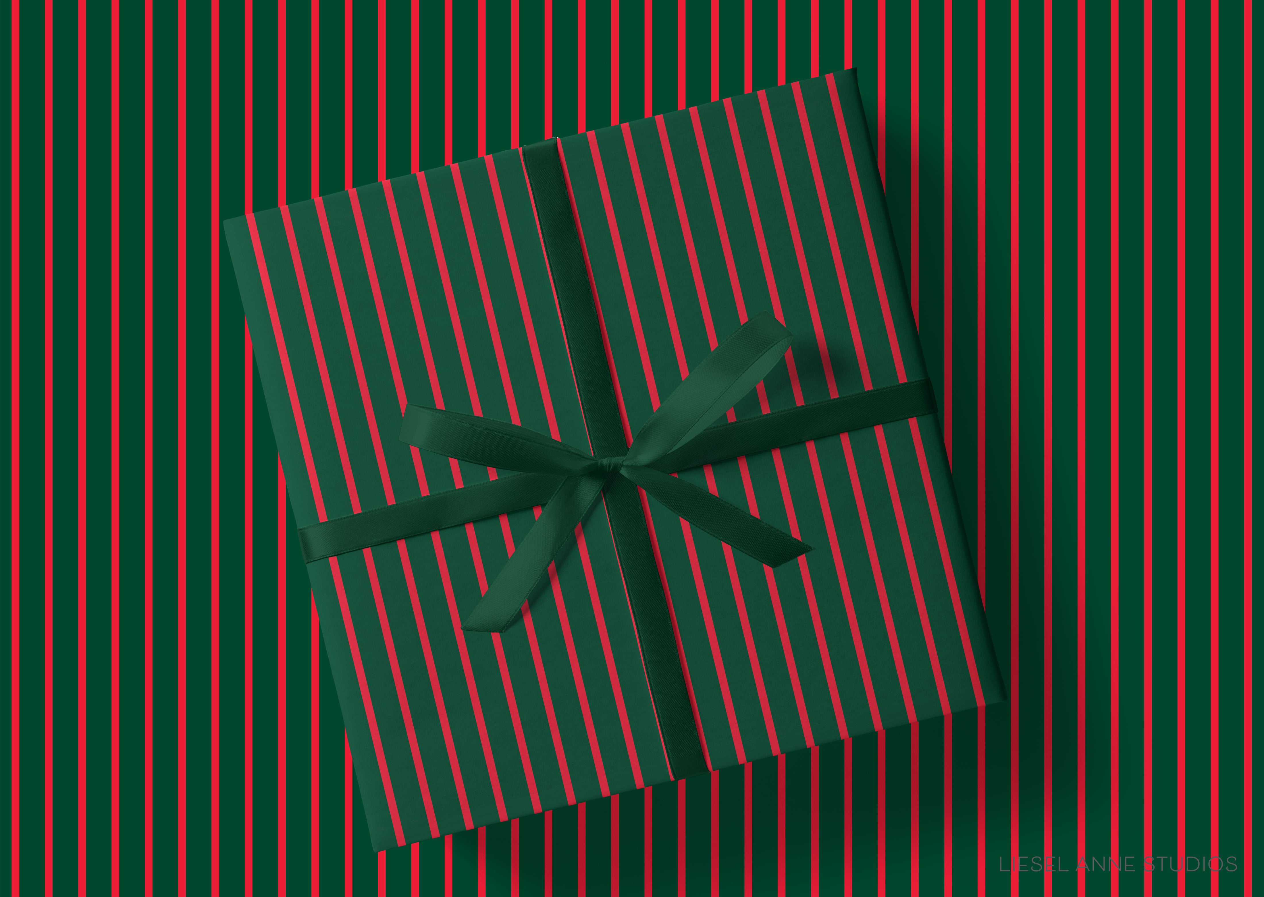 A green gift box with a red ribbon tied around it, placed on a background with red and green striped patterns.