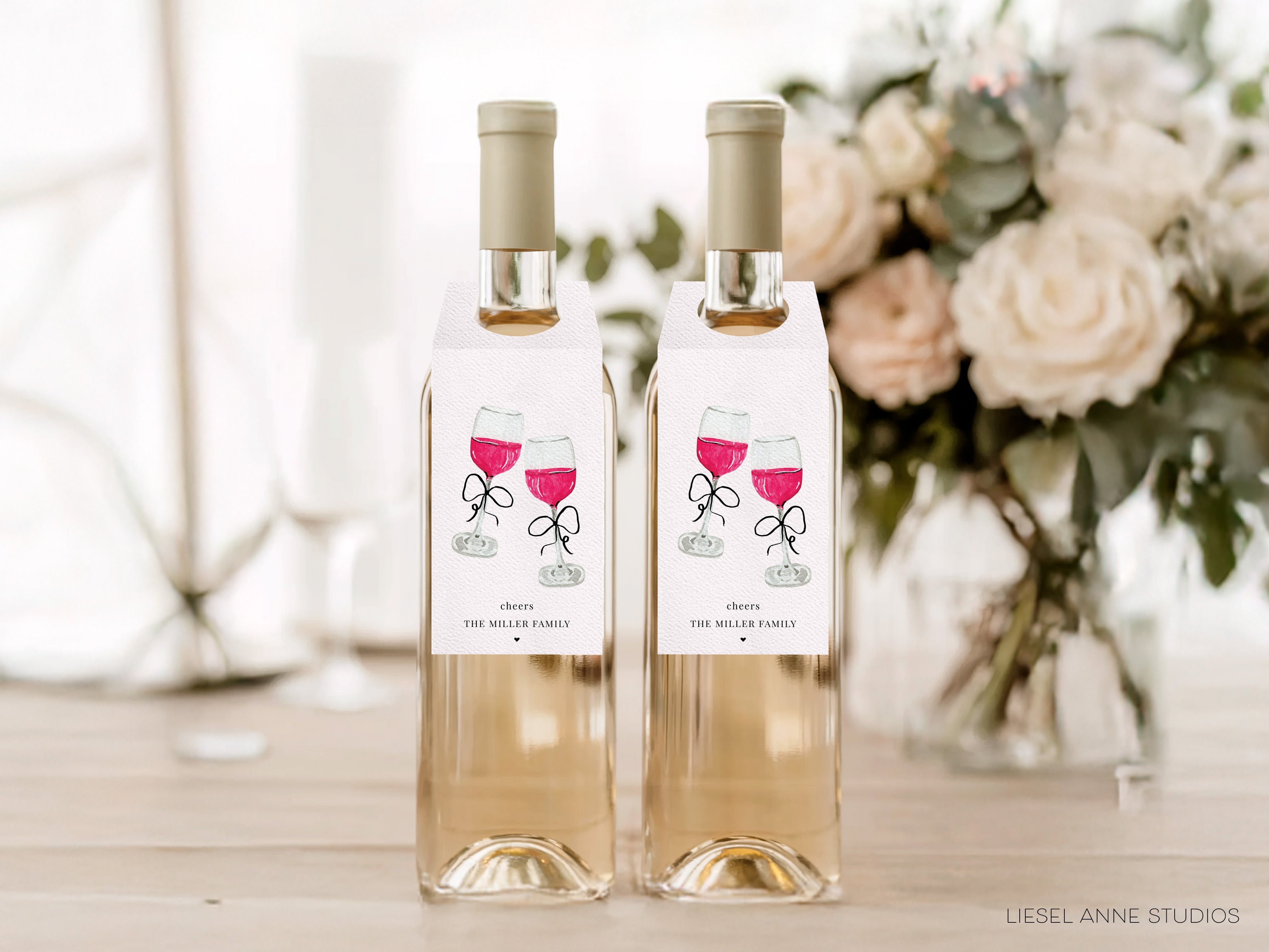 Two bottles of wine with labels that say "Cheers The Miller Family" and "Cheers The Miller Family" respectively, placed on a wooden surface in front of a vase of white flowers.