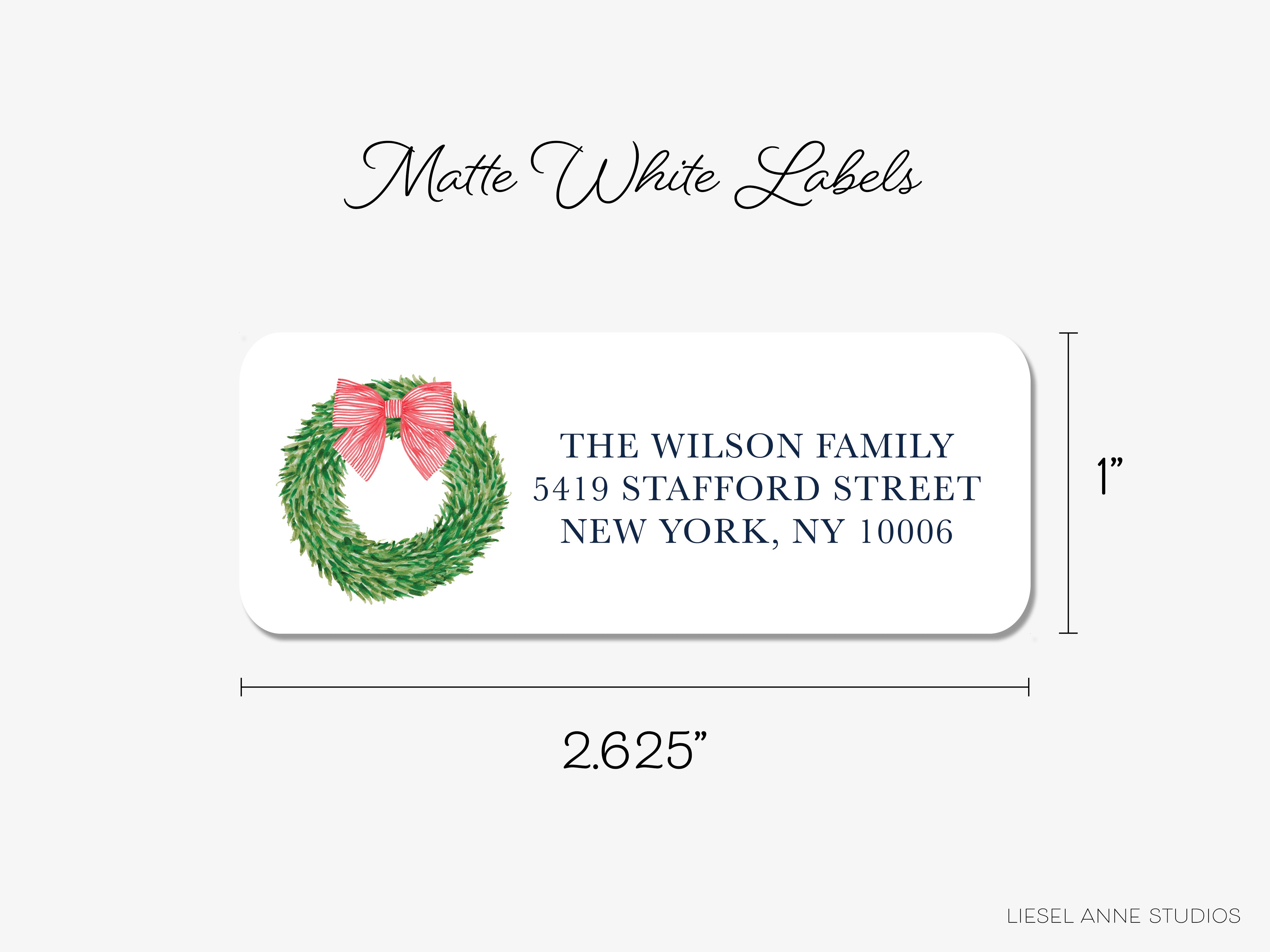 The image is a label for a Christmas-themed envelope, featuring a wreath and a pink bow. The label is from Liesel Anne Studios and has dimensions of 2.65 inches by 2.65 inches.