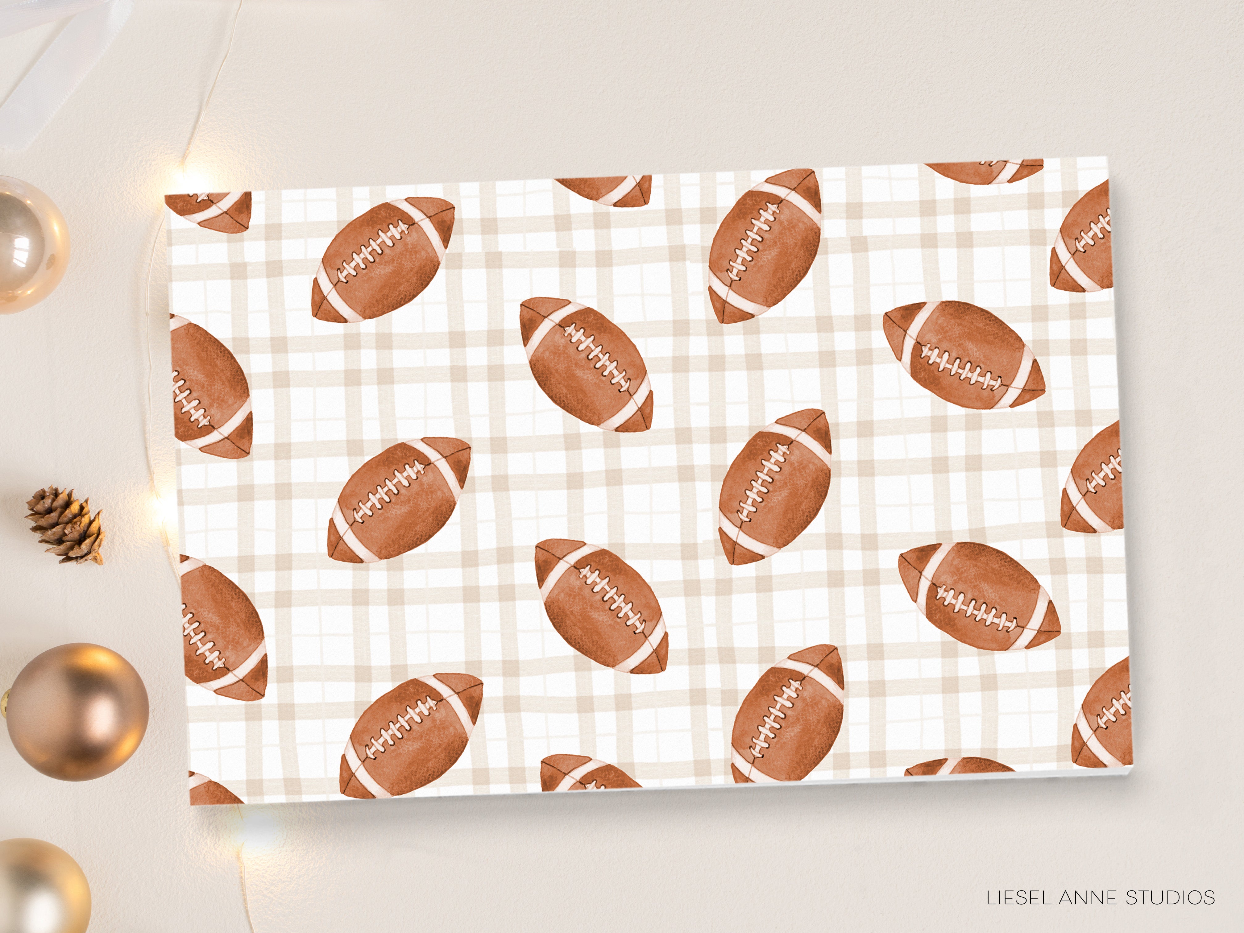 a repeating pattern of brown footballs on a white background, with the text "Liesel Anne Studios" visible in the bottom right corner.