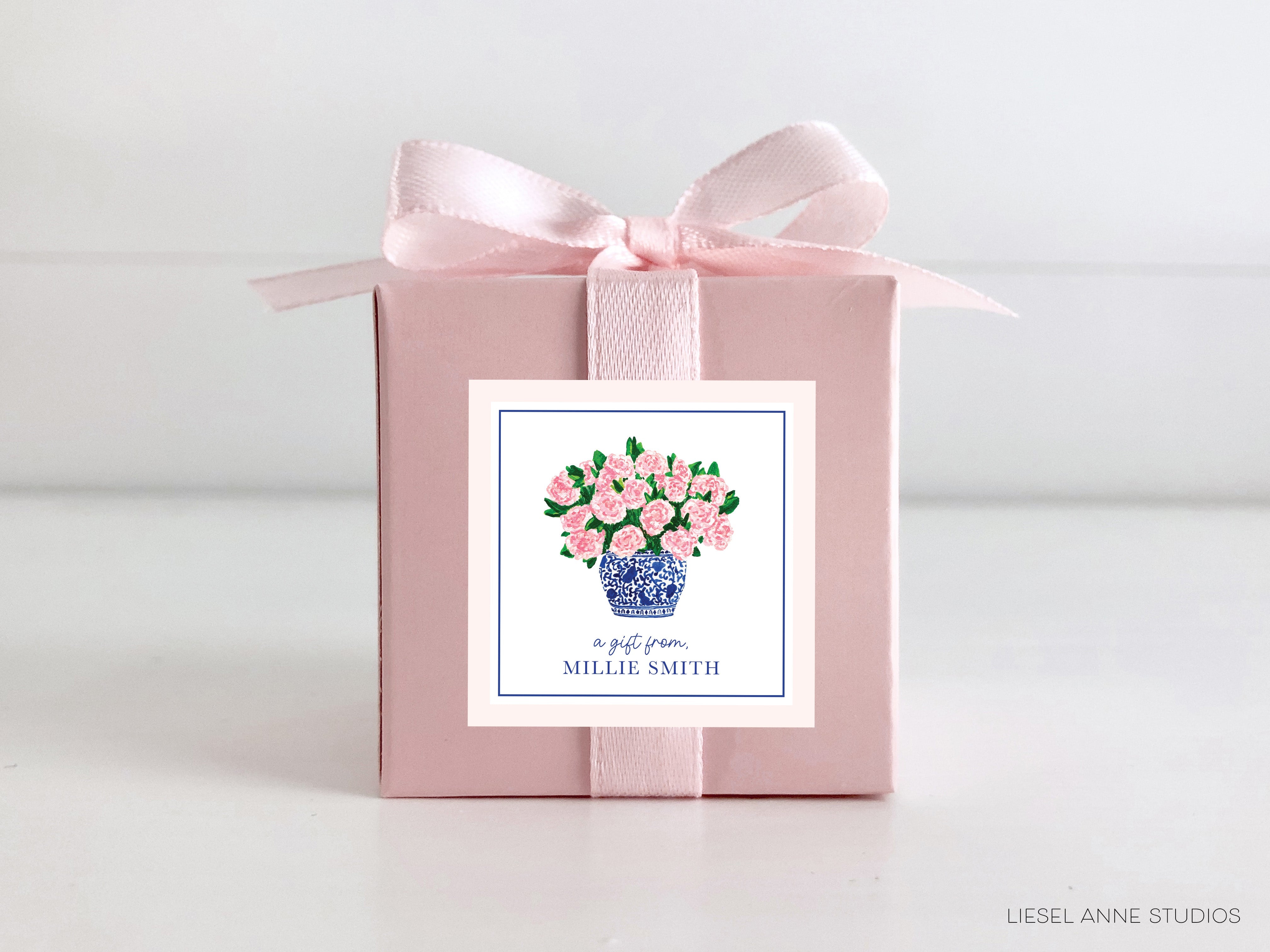 a pink gift box with a pink ribbon and a blue vase with pink flowers