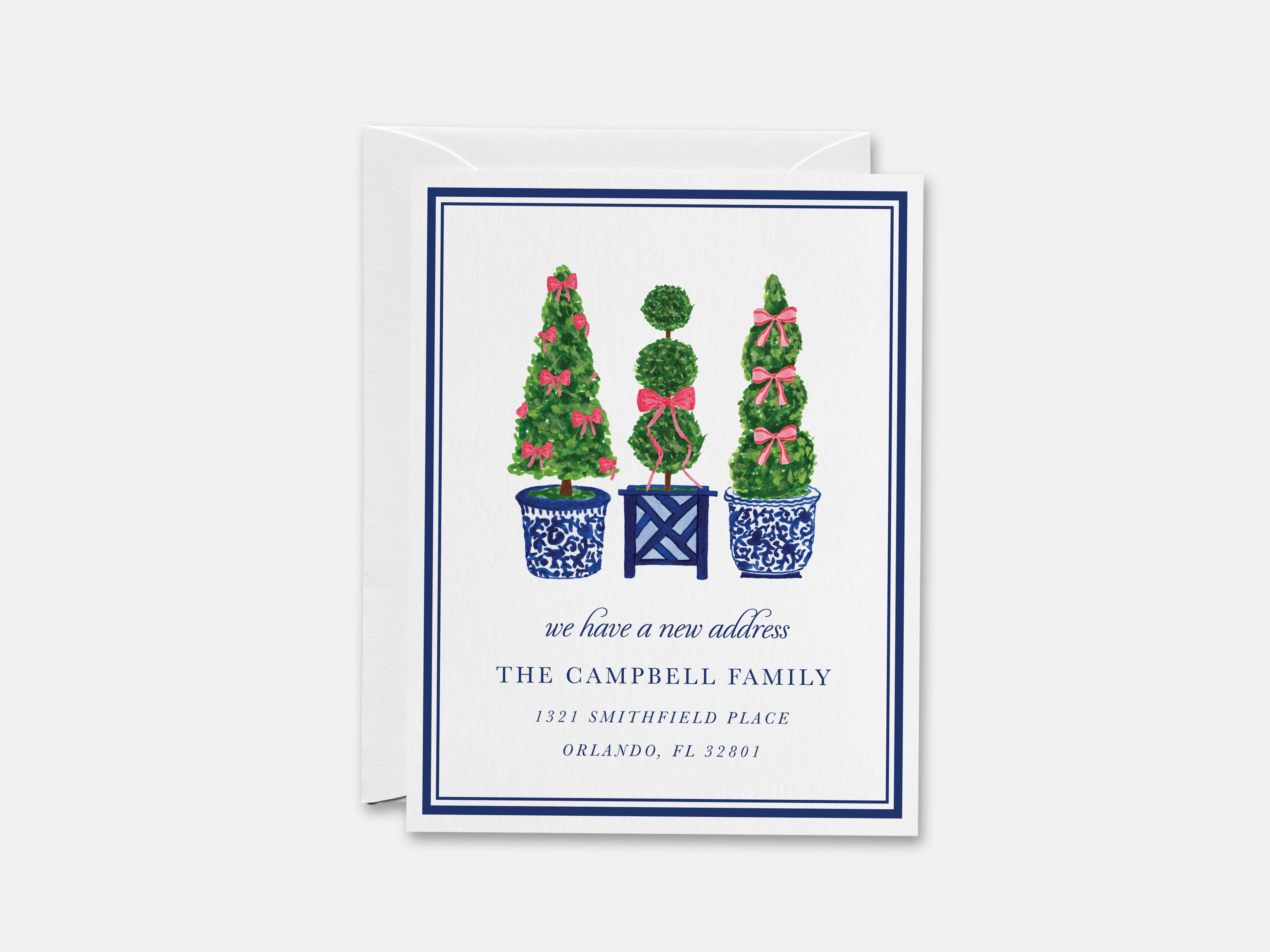 The image is a greeting card with a design featuring three topiary trees in blue and white pots, along with a text box that reads "we have a new address".