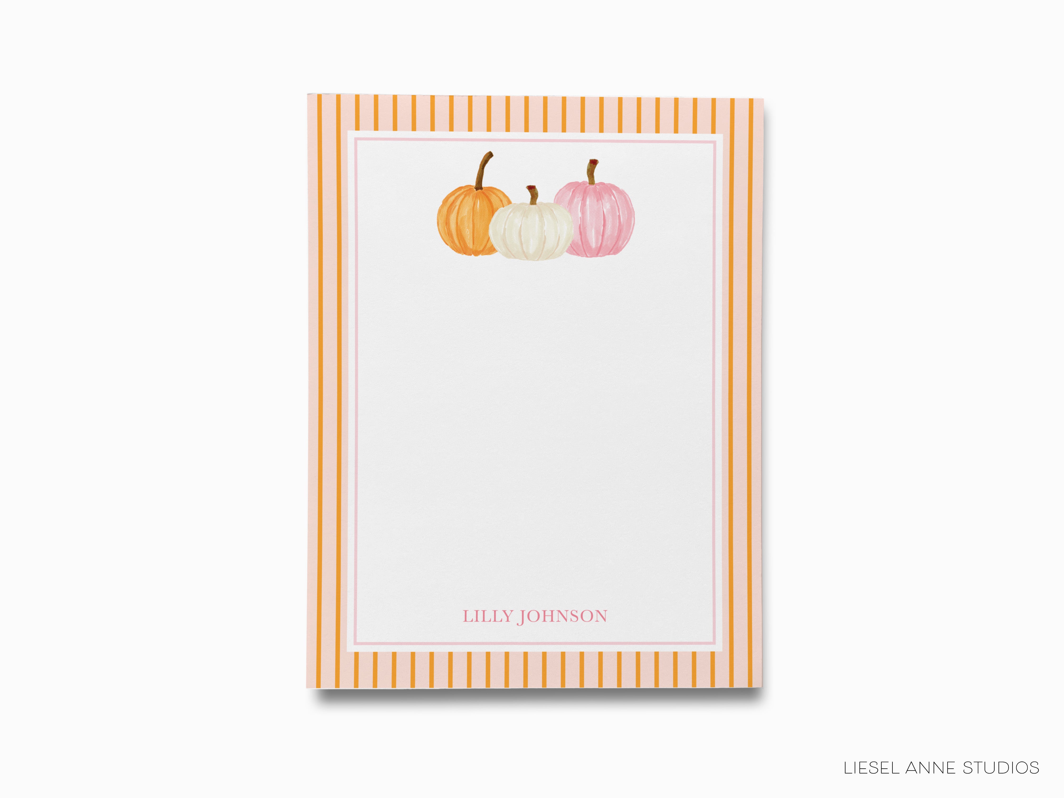 A white card with a striped border, featuring three pumpkins of different colors - orange, white, and pink - on the top.