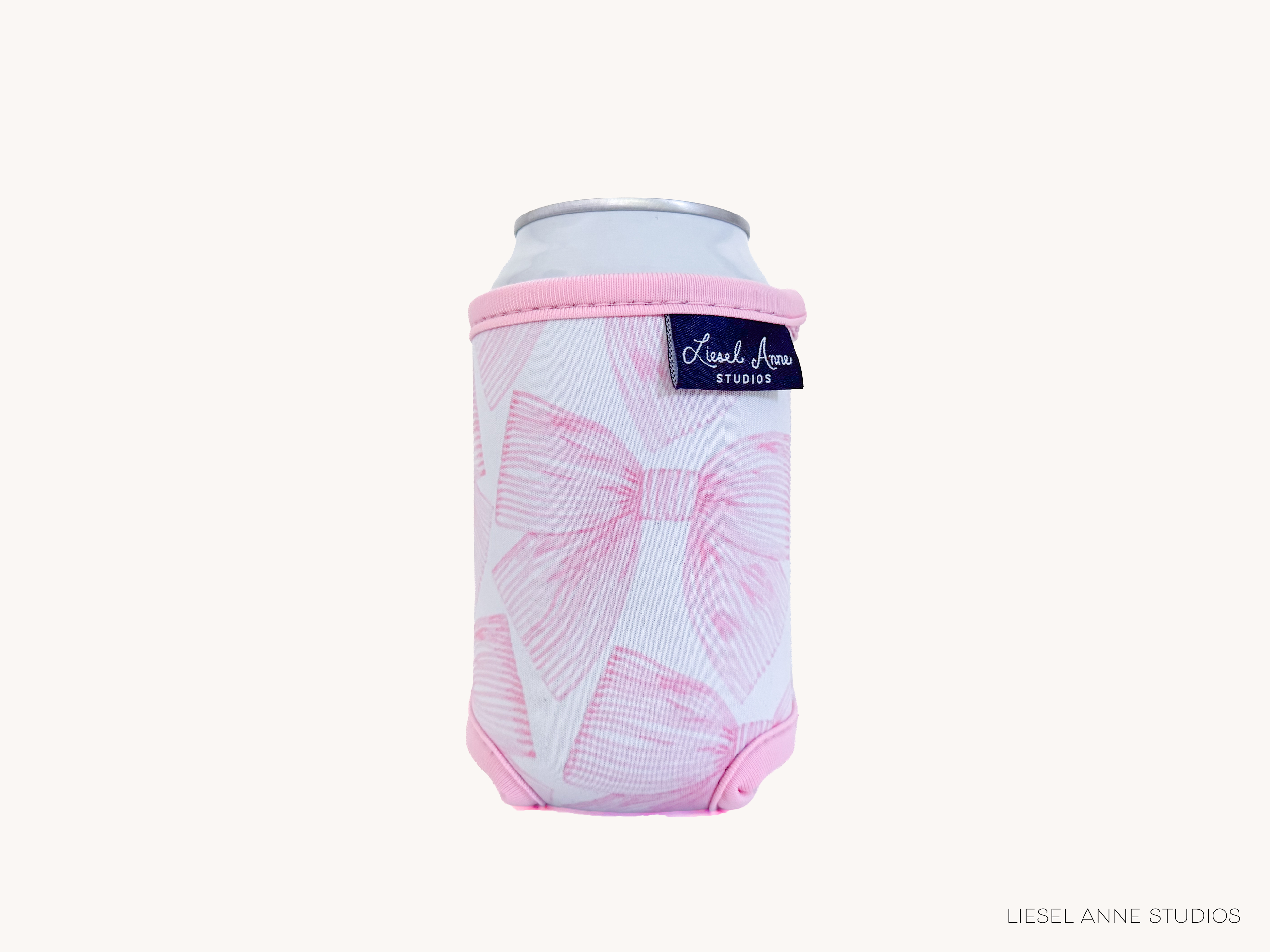 A pink and white patterned can holder with a label that says "Liesel Anne Studios".