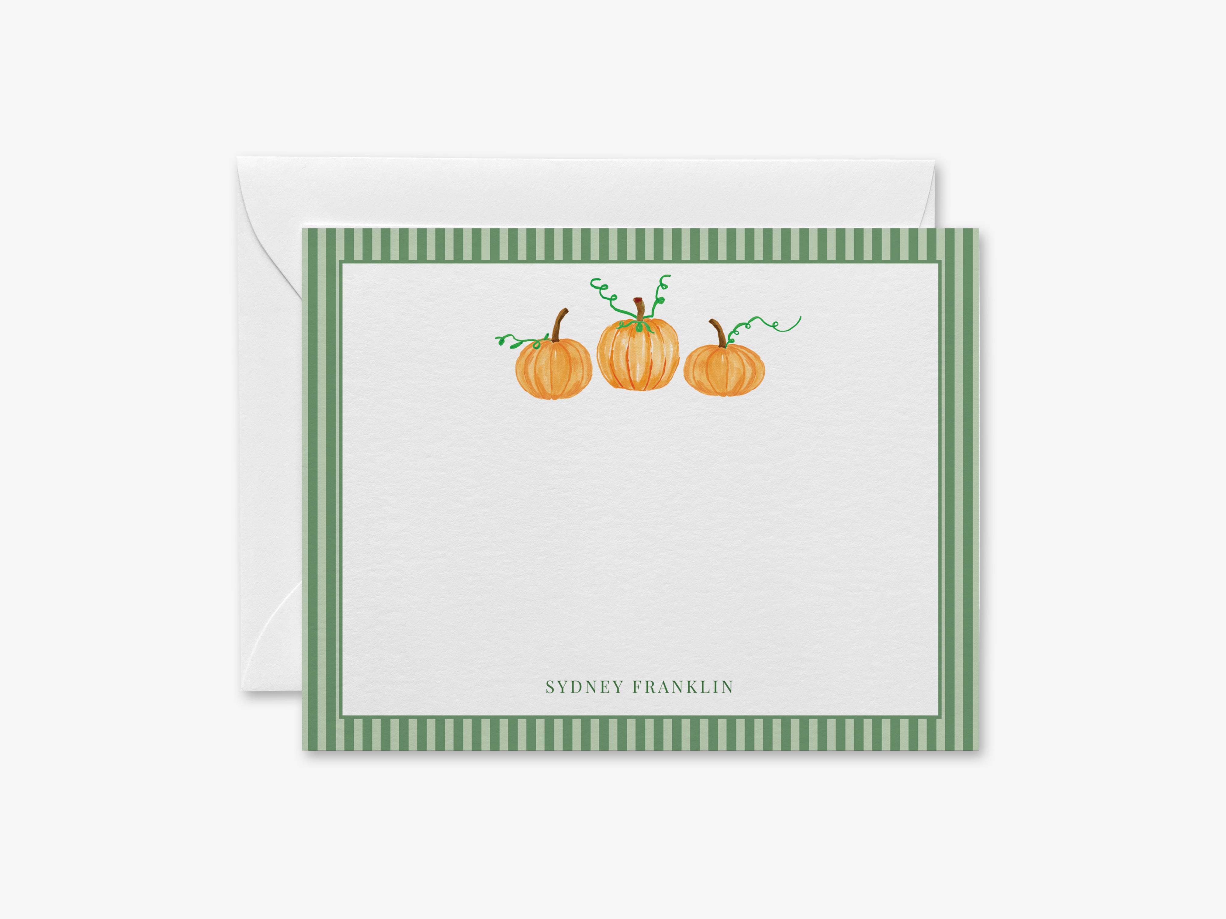 A green and white striped card with three pumpkins on it, placed on top of an envelope.