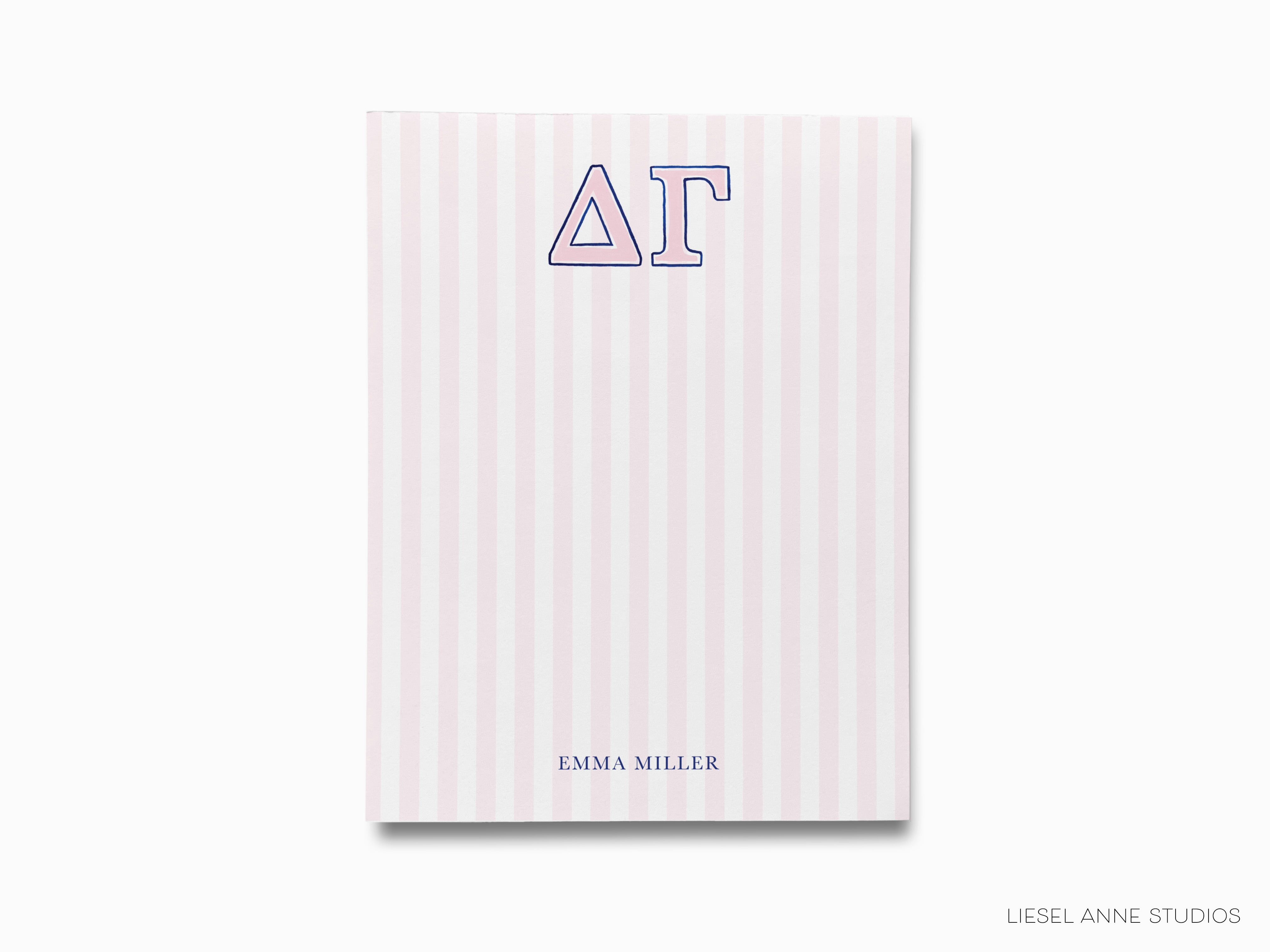 a pink and white striped notebook with the letter at on it