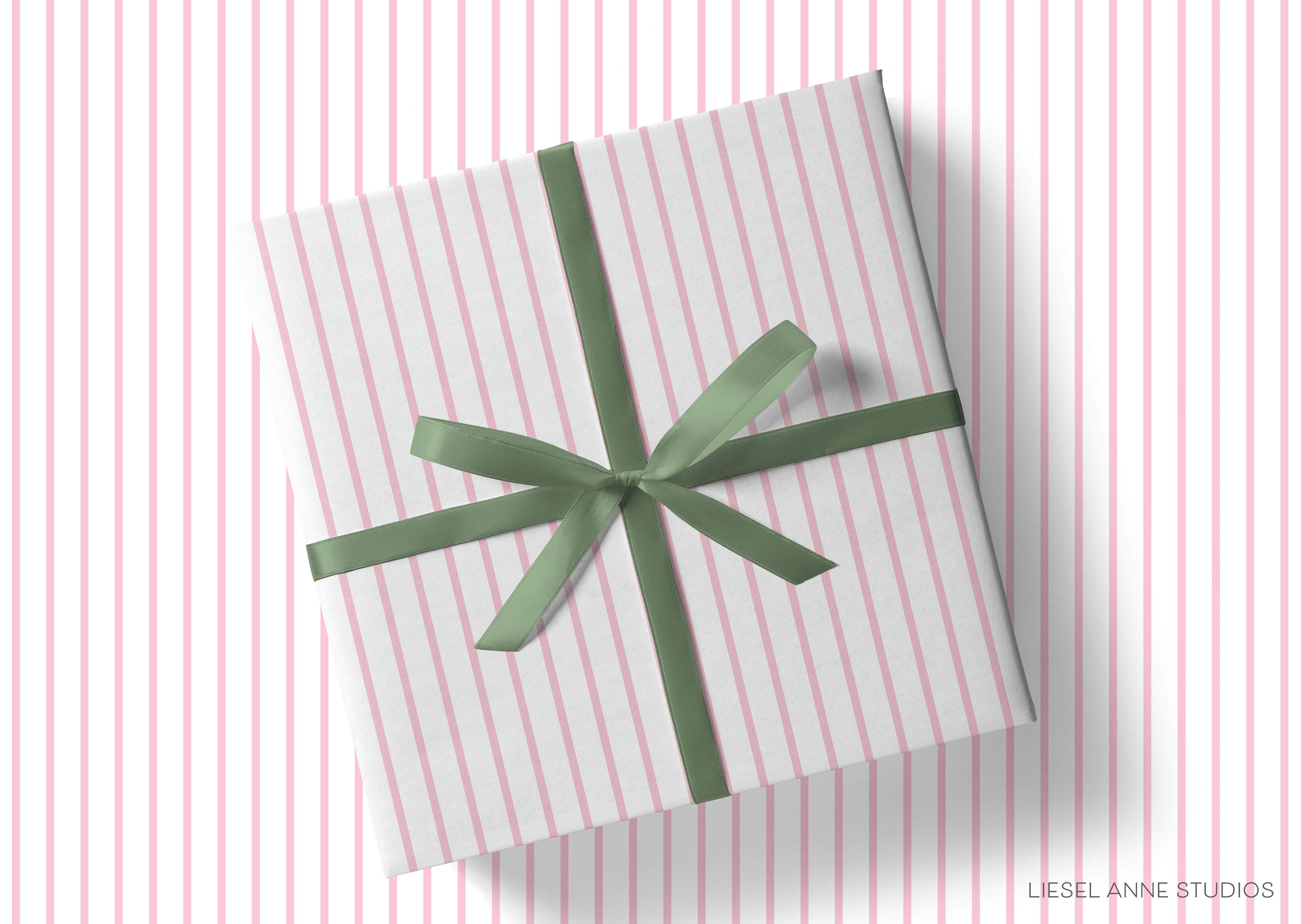 A gift box wrapped in a white and pink striped paper with a green ribbon bow tied around it.