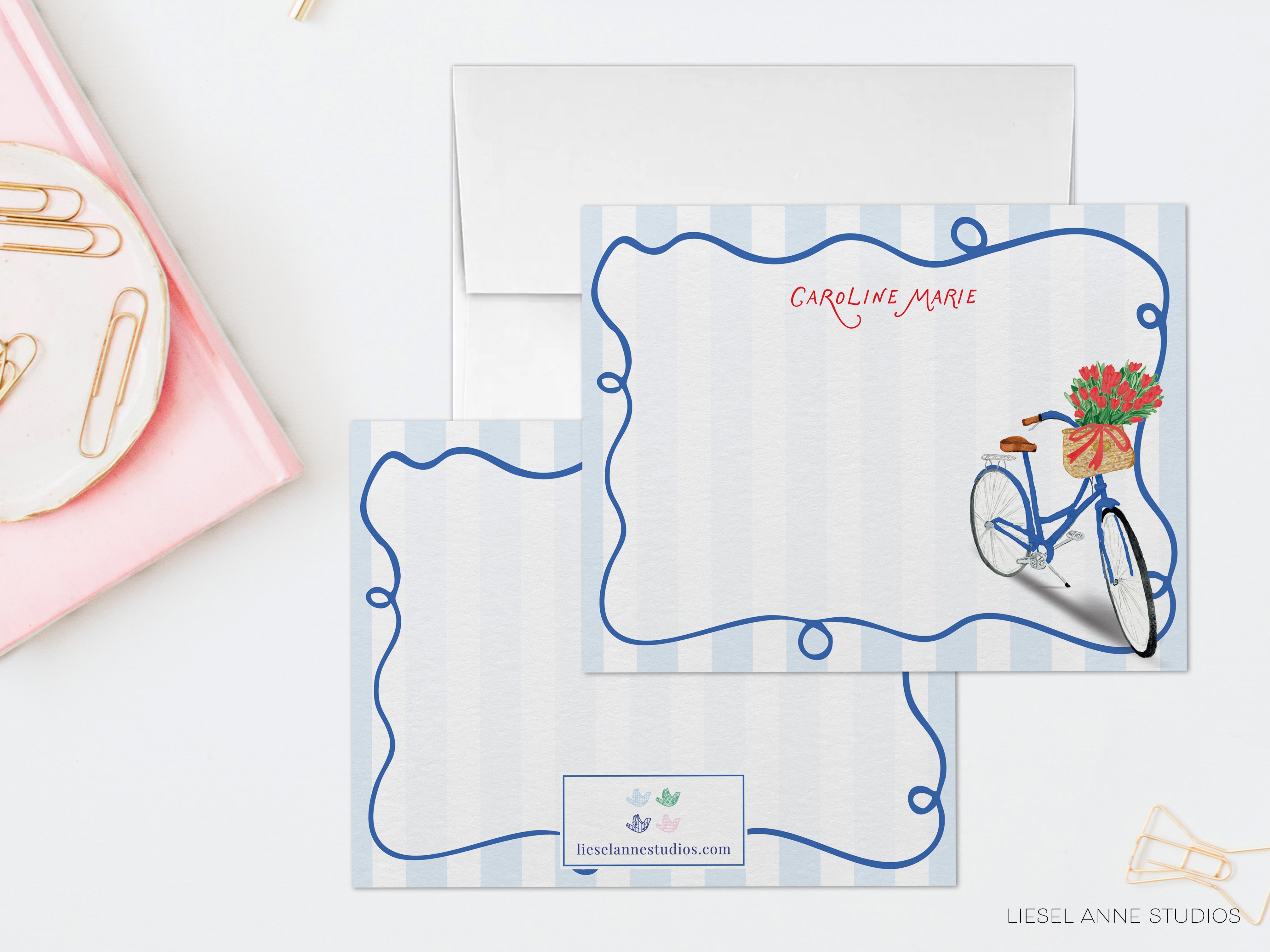a set of blue and white stationery items, including an envelope and a card, with a bicycle illustration on the card.