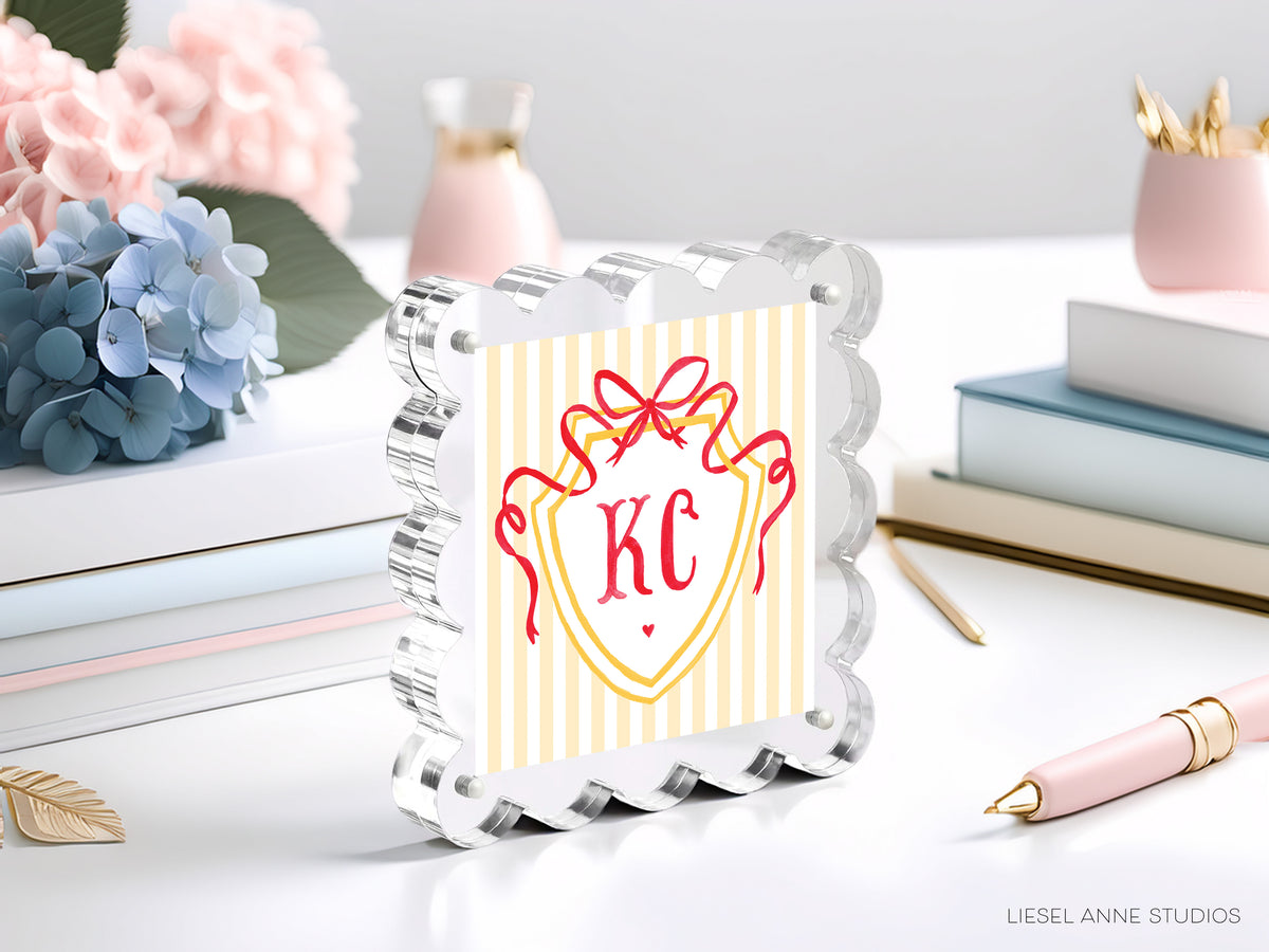 a decorative glass frame with a shield-shaped design, surrounded by various office supplies and decorative items such as flowers and books.