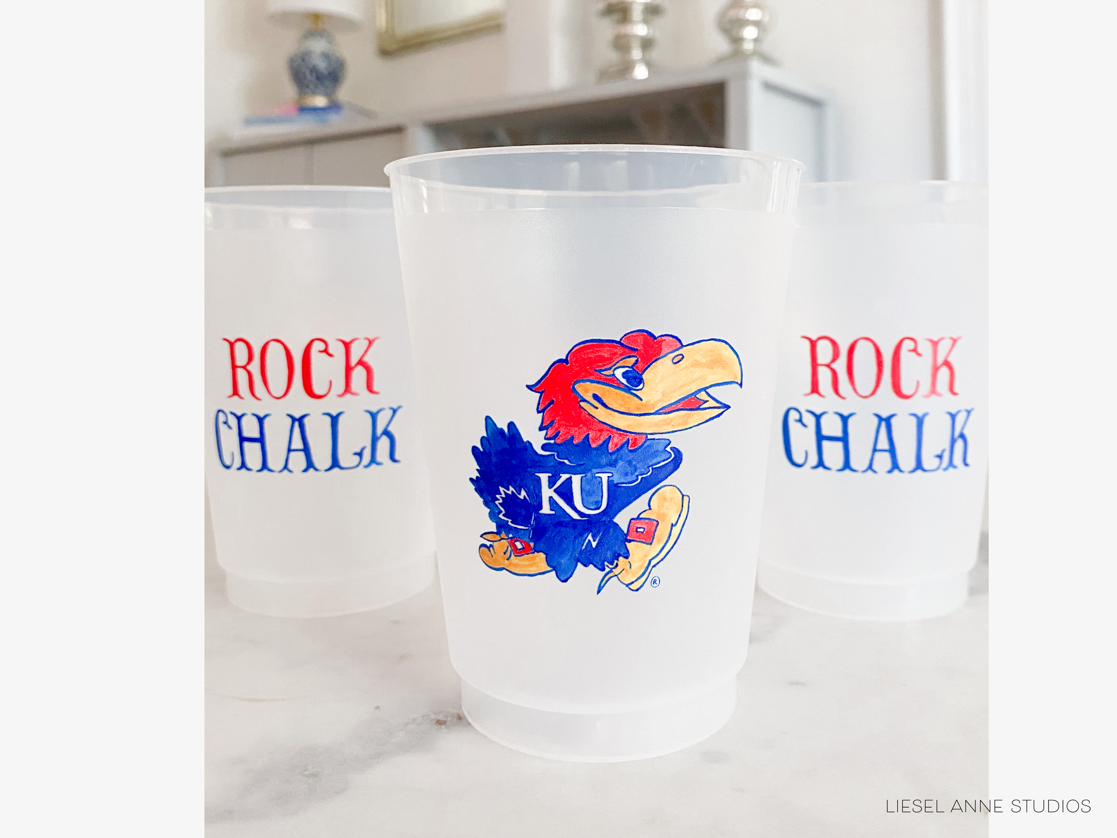 Three white plastic cups with red and blue text and an illustration of a bird, likely representing a sports team or mascot.