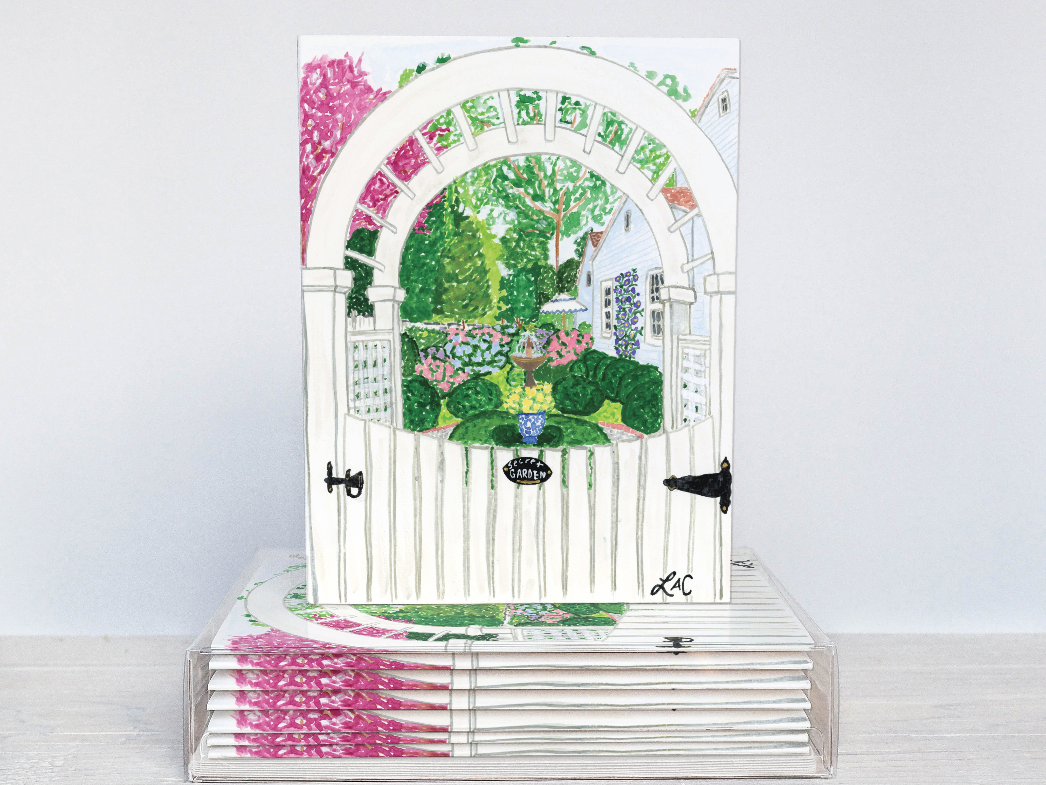 A white wooden gate with a colorful garden scene behind it, set against a white background.