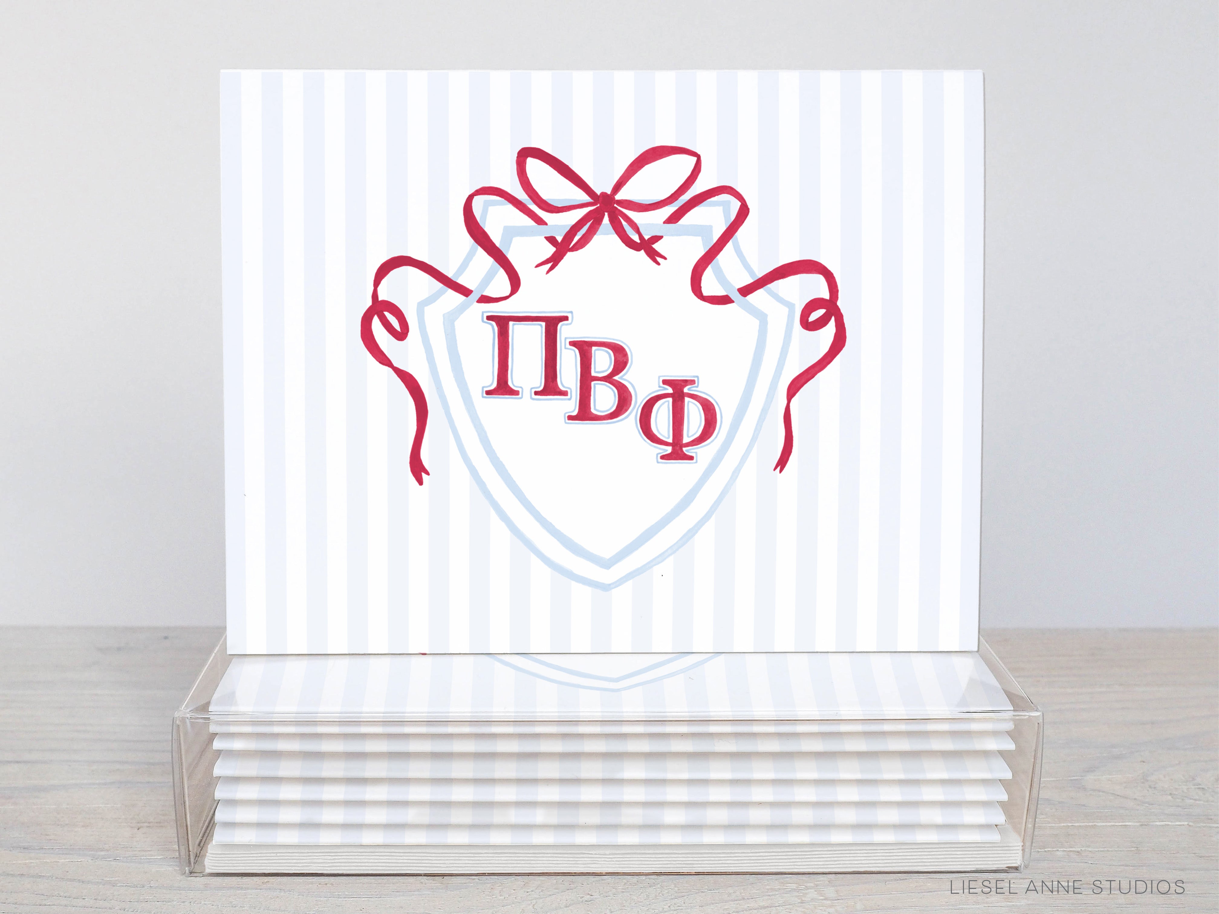 A stack of white greeting cards with a red ribbon and a shield-shaped design featuring the Greek letters "ΦΦΦΦ" (ΦΦΦΦ).