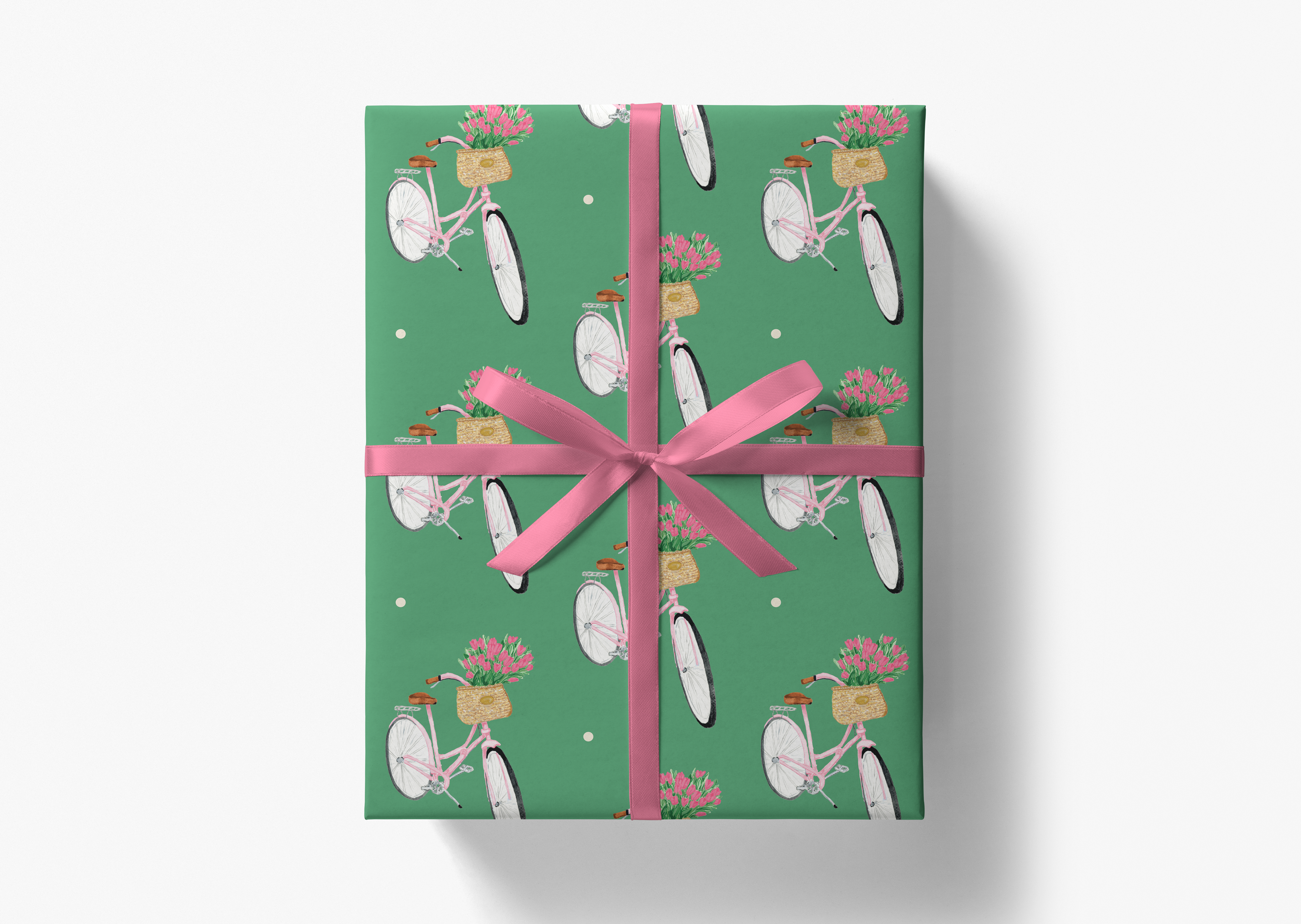 A gift box wrapped in a green paper with a pink ribbon, featuring a repeating pattern of bicycles and baskets with flowers.