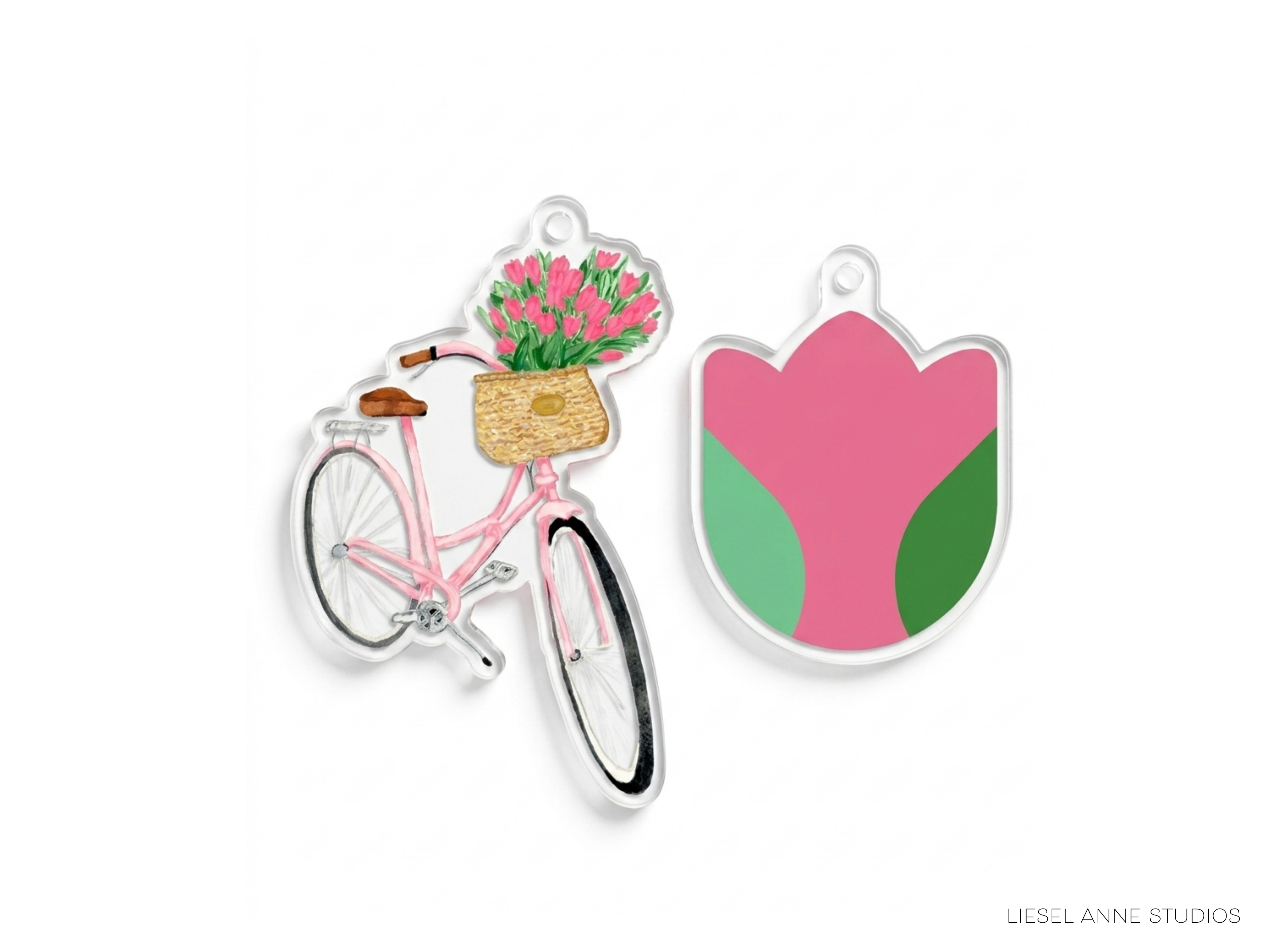 two clear plastic charms, one depicting a bicycle with a basket of flowers and the other depicting a pink flower in a pink and green shape.