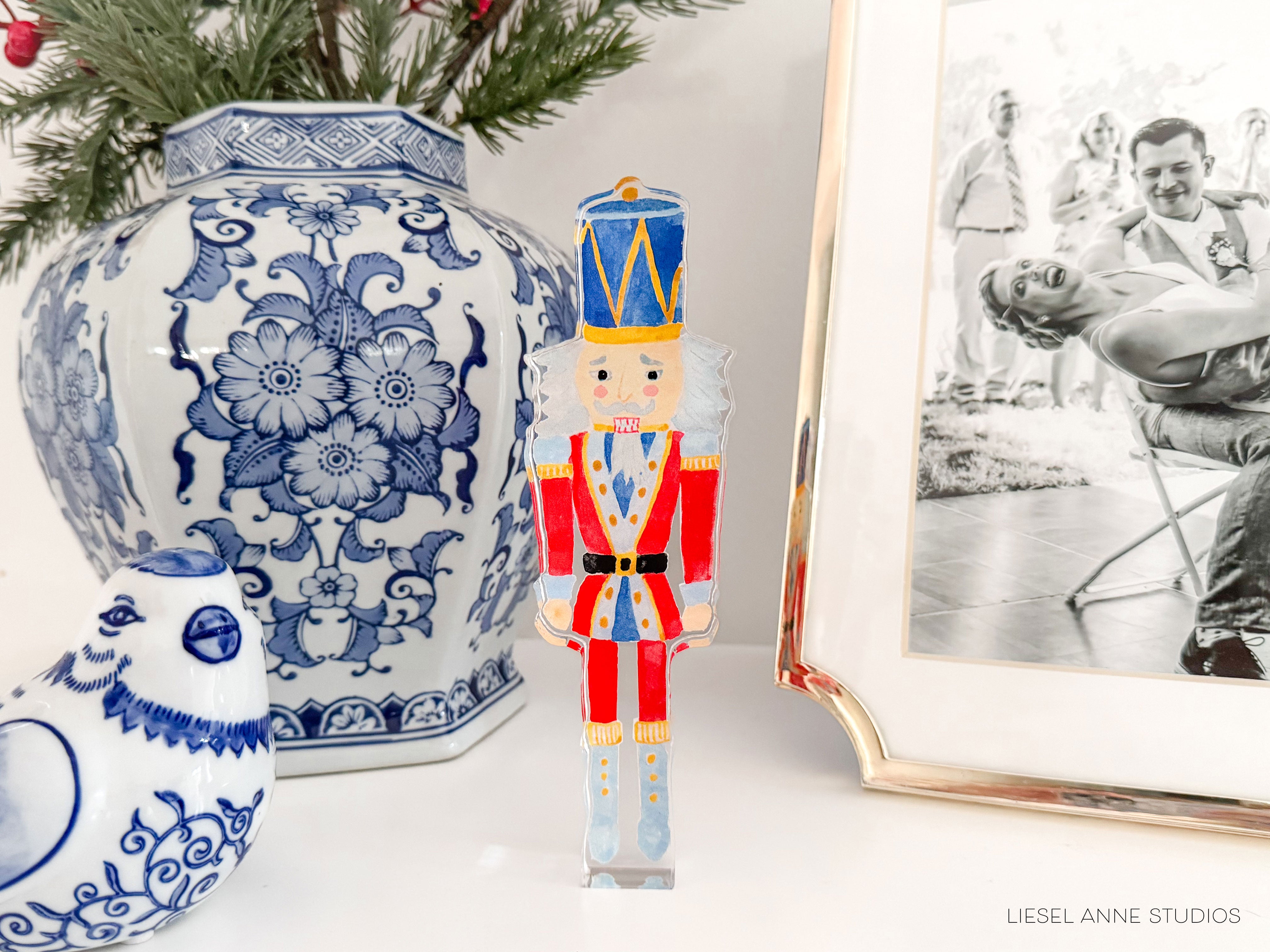 a blue and white porcelain vase with a floral design, a nutcracker figurine, a small bird figurine, and a framed black and white photograph of a family.