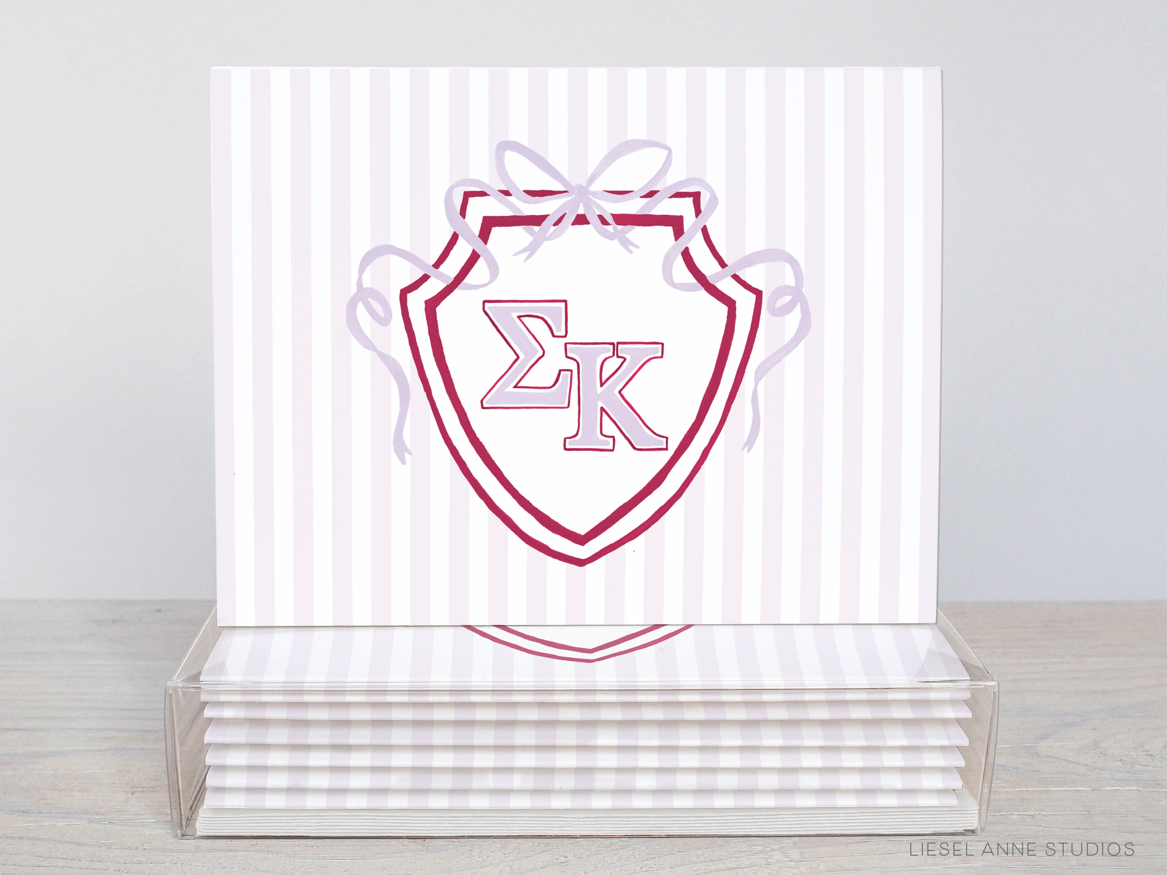 A stack of white and red striped greeting cards with a shield-shaped logo featuring the letters 'EK' in the center.