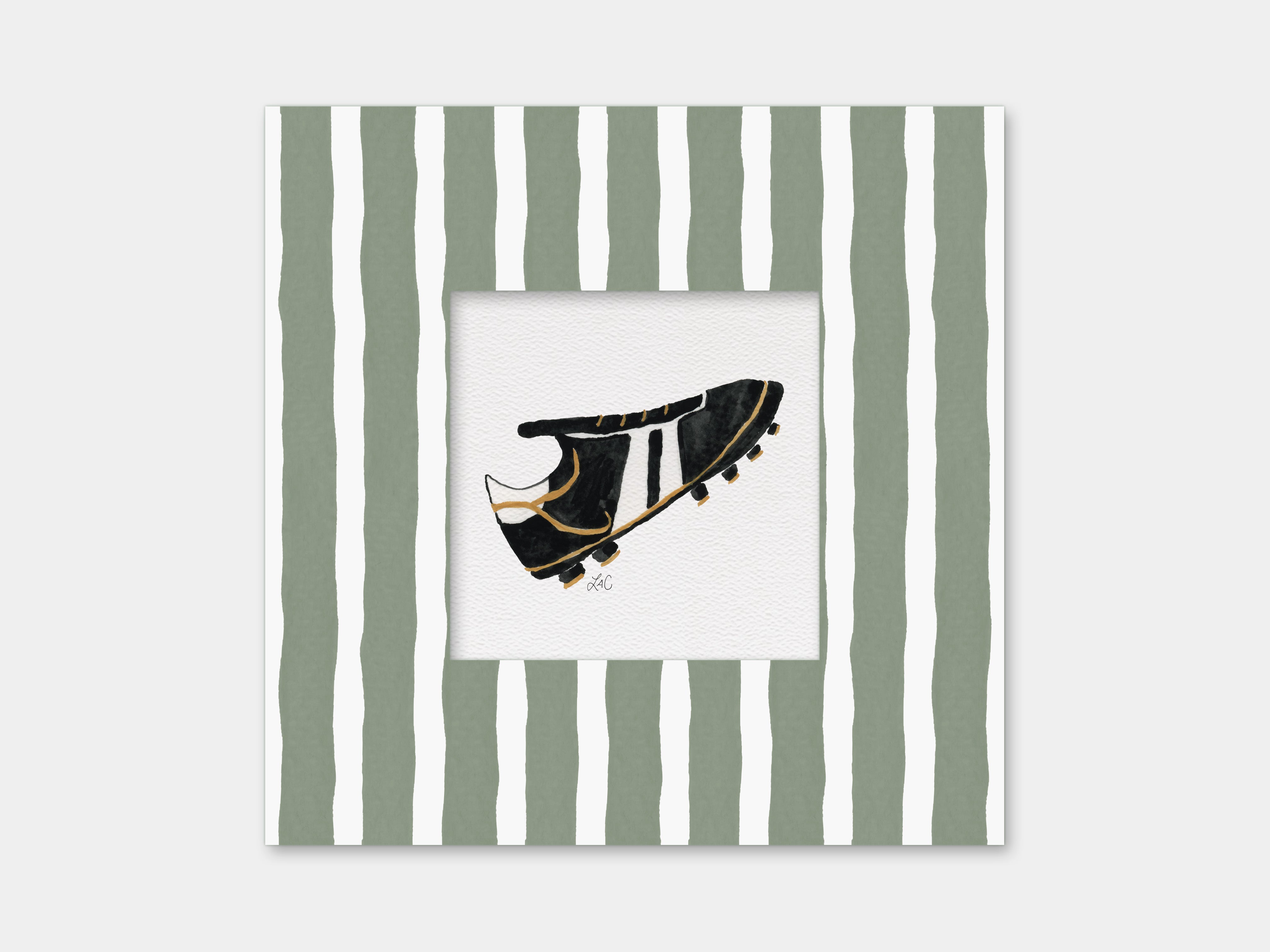 A framed image of a black and gold soccer cleat against a white background.