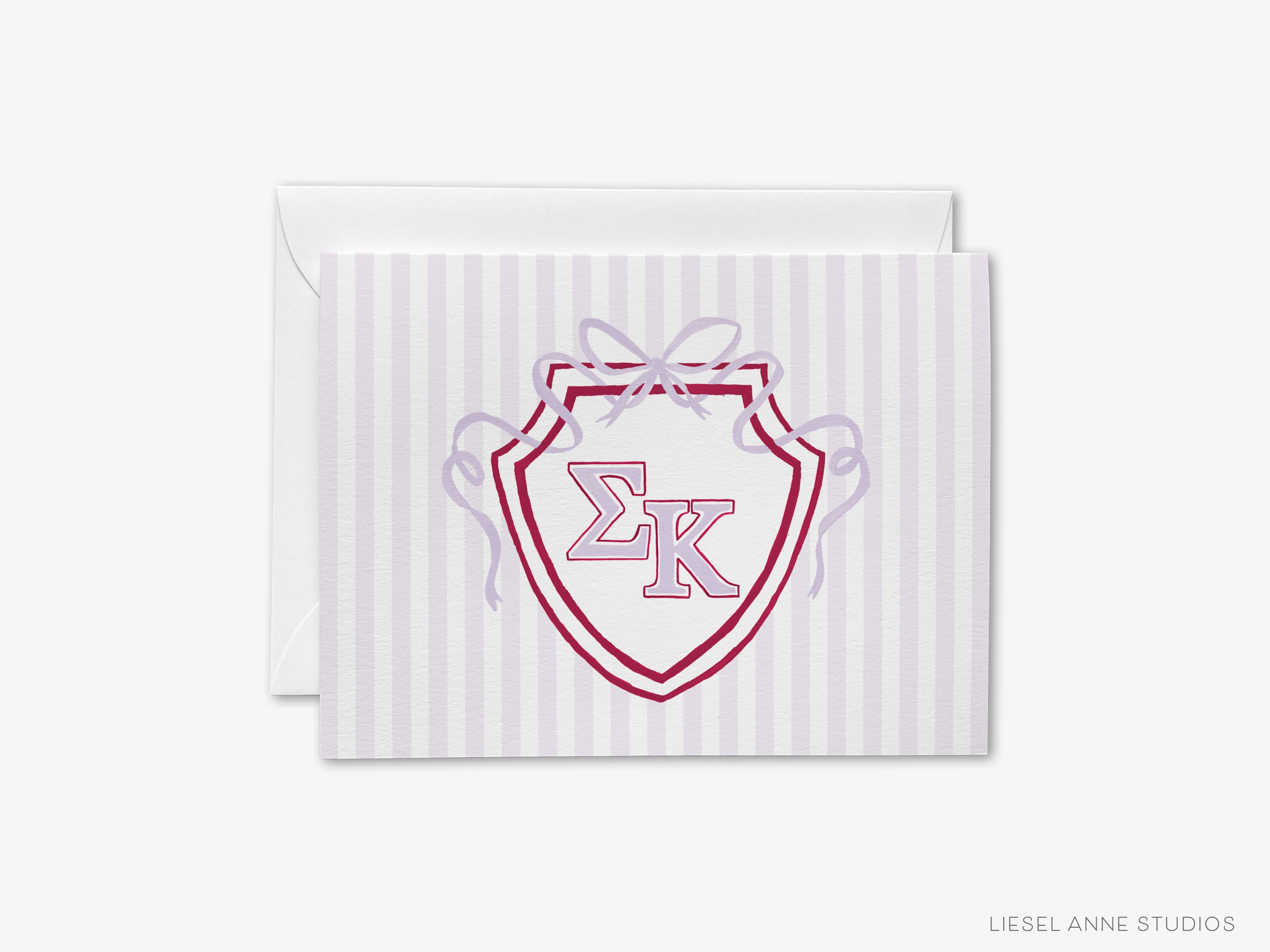 A greeting card with a shield-shaped design featuring the letters 'EK' in the center, surrounded by a ribbon.