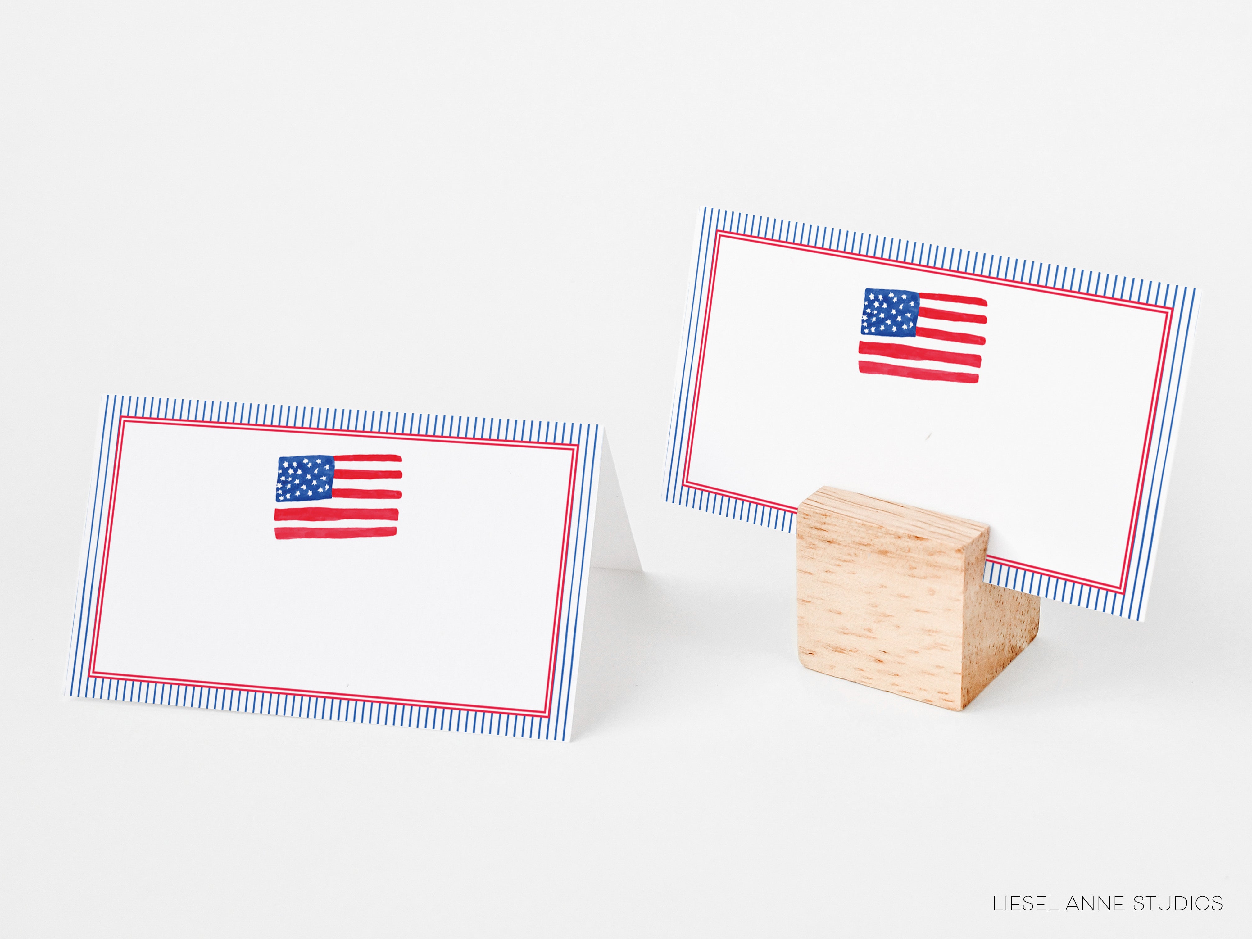 two blank place cards with a patriotic American flag design, placed on a wooden stand.