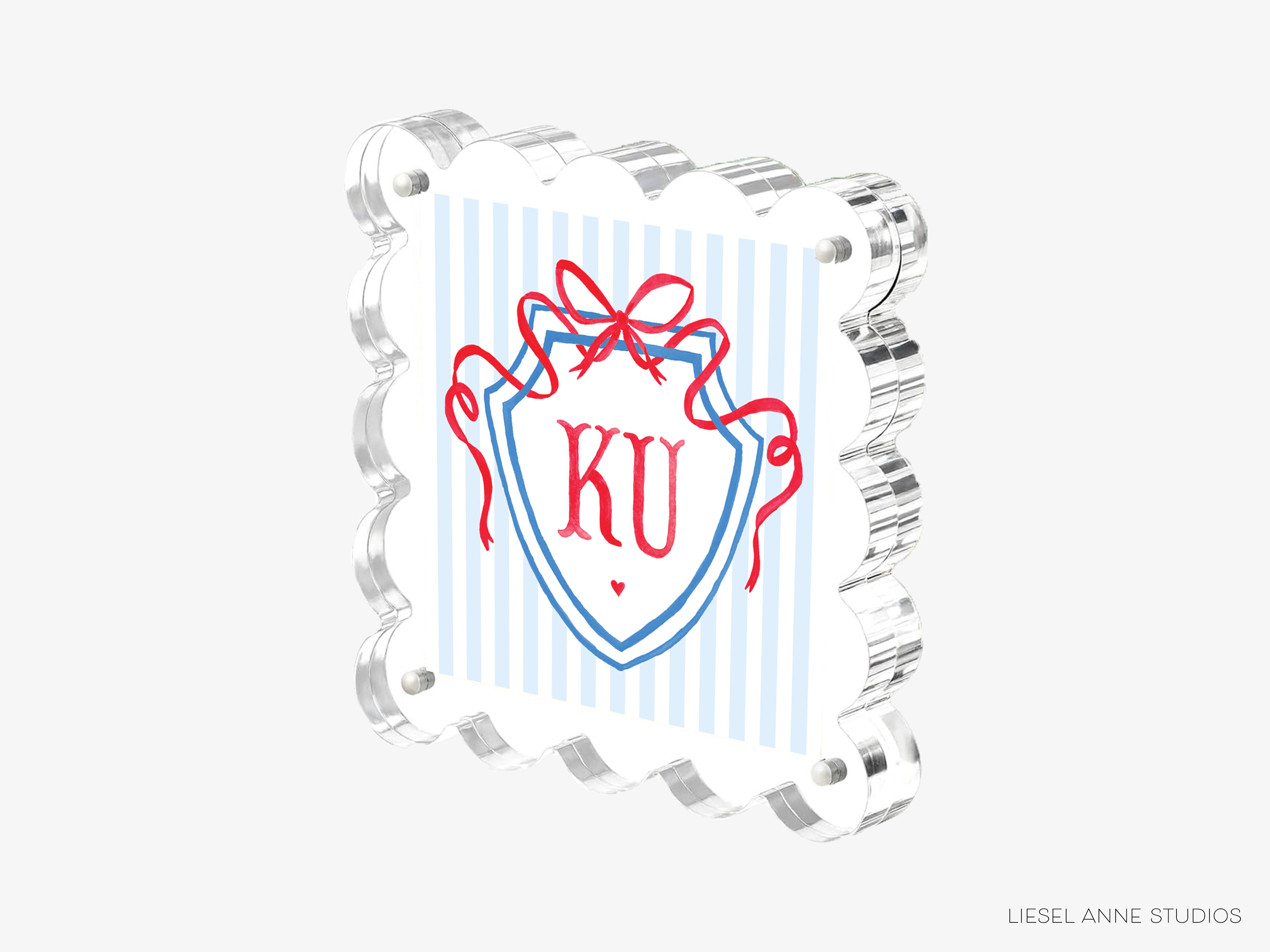 A square, clear acrylic frame with a decorative border and a shield-shaped design featuring the letters 'KU' in red and blue.