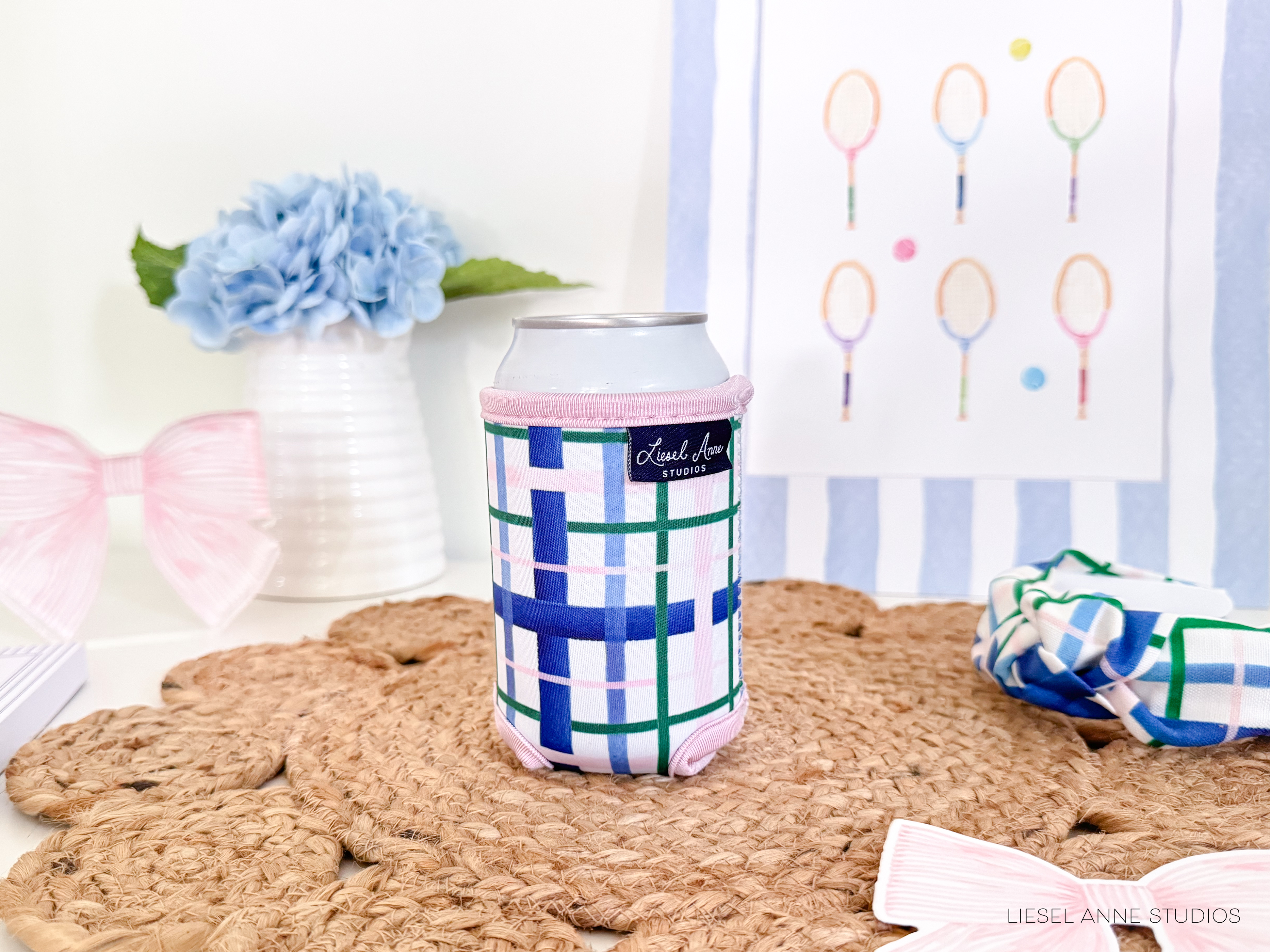 a can with a checkered pattern, a vase with blue flowers, a woven mat, and a framed tennis racket drawing on a wall.