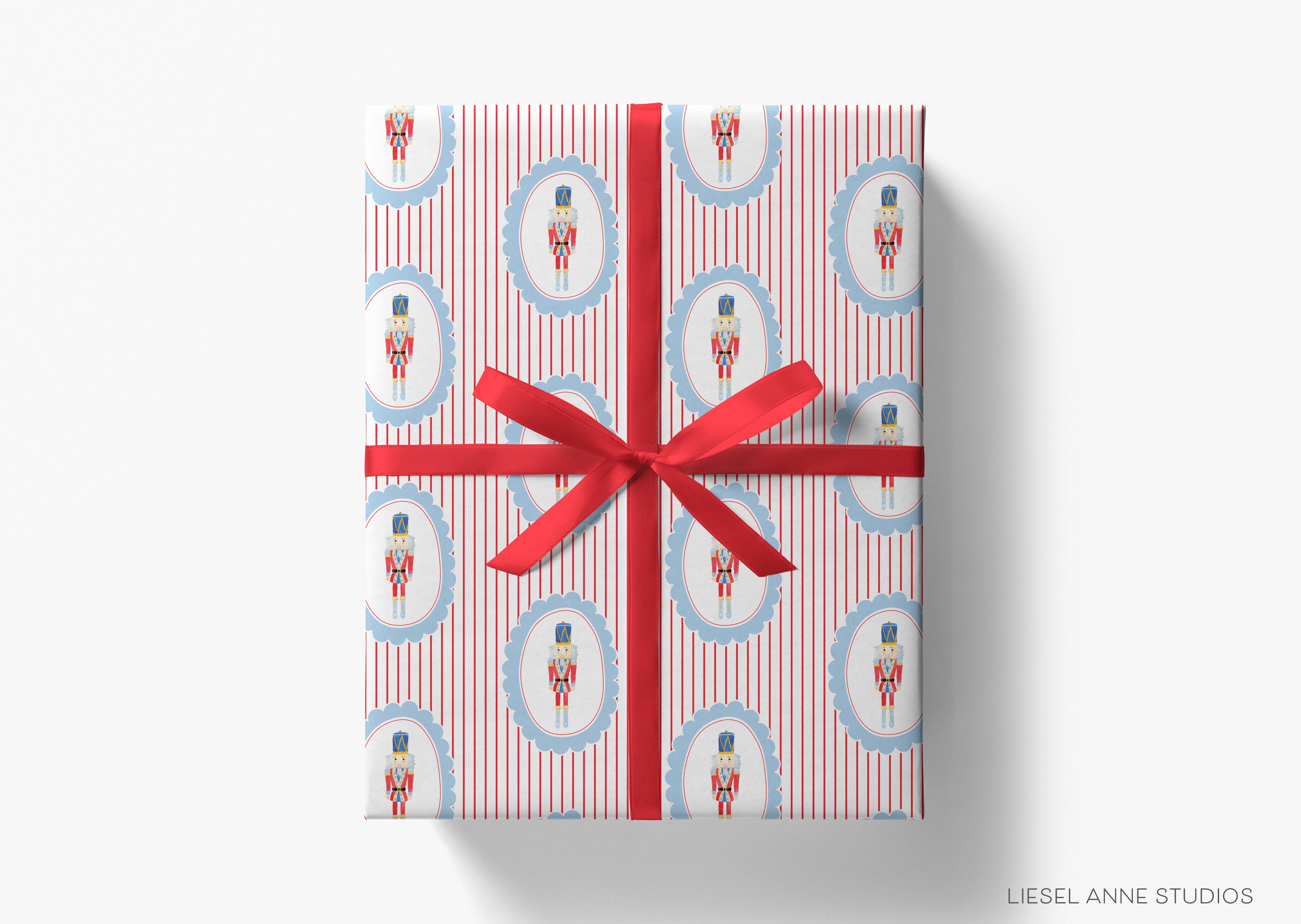 A gift box wrapped in red and white striped paper with a red ribbon bow. The paper has a repeating pattern of nutcracker images and blue frames.