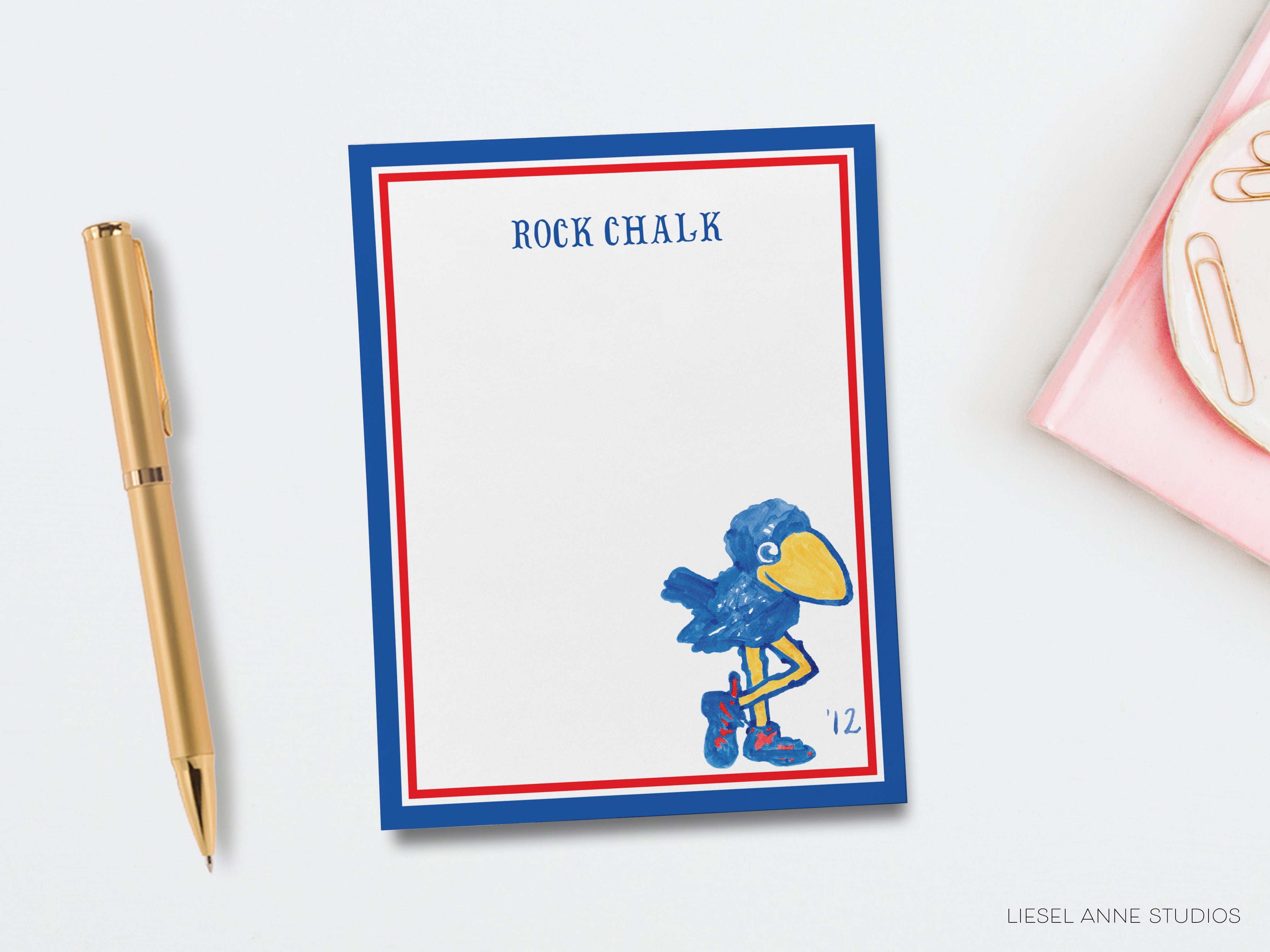 a blue and red post-it note with a cartoon bird illustration, a gold pen, and a pink object on a white background.
