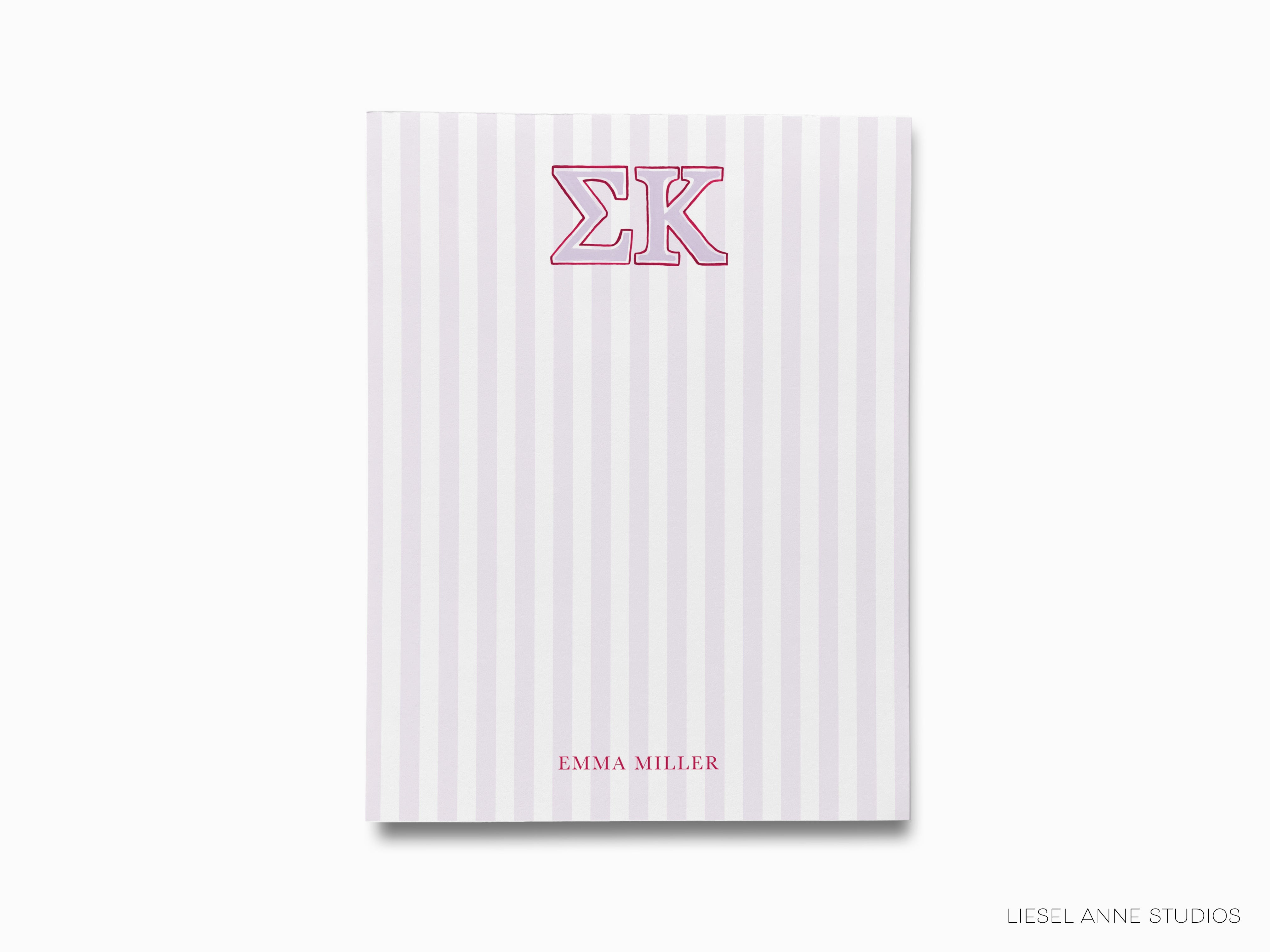 a pink and white striped notebook with the letter k on it