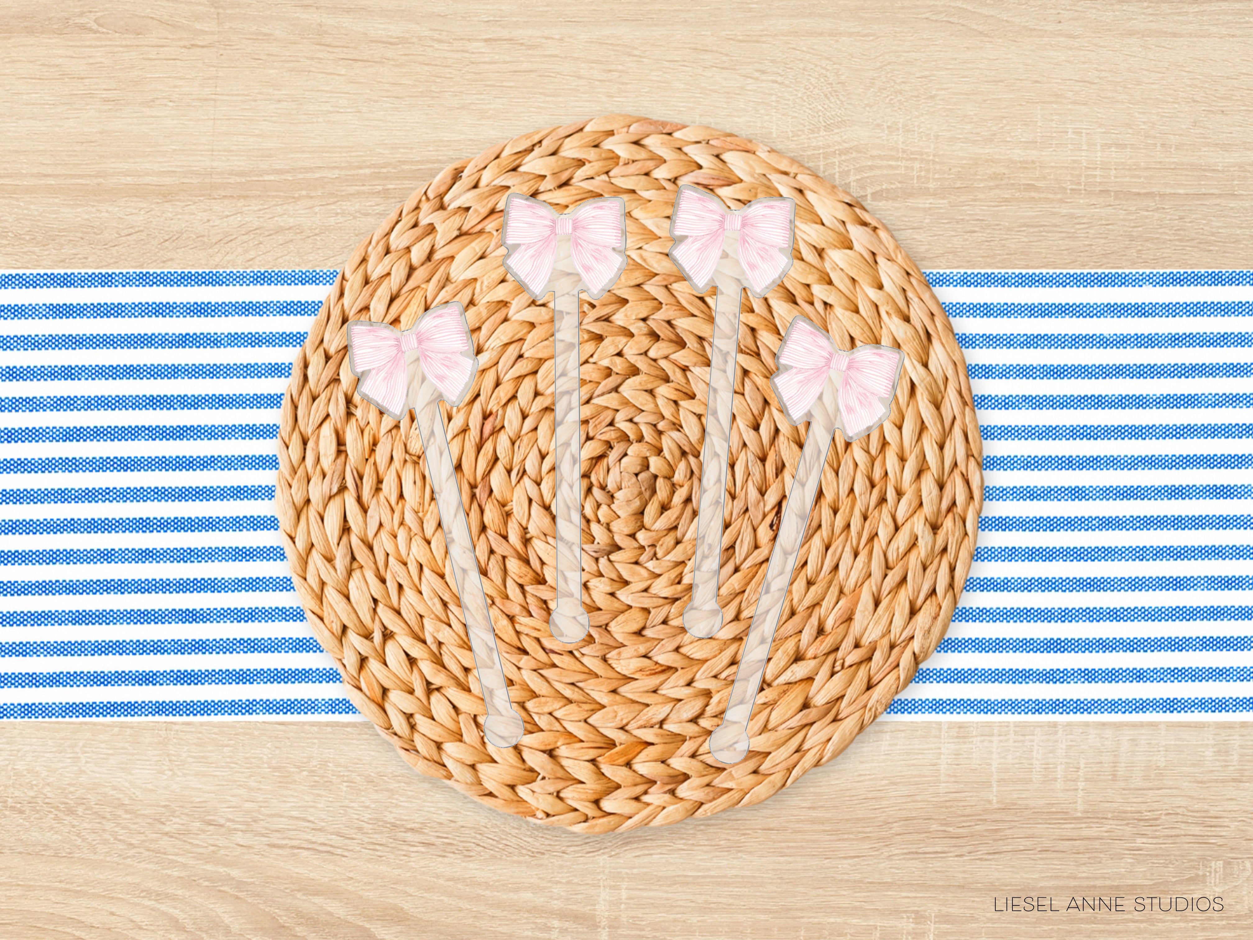 A woven placemat with pink bows on a wooden table, placed on a blue and white striped cloth.