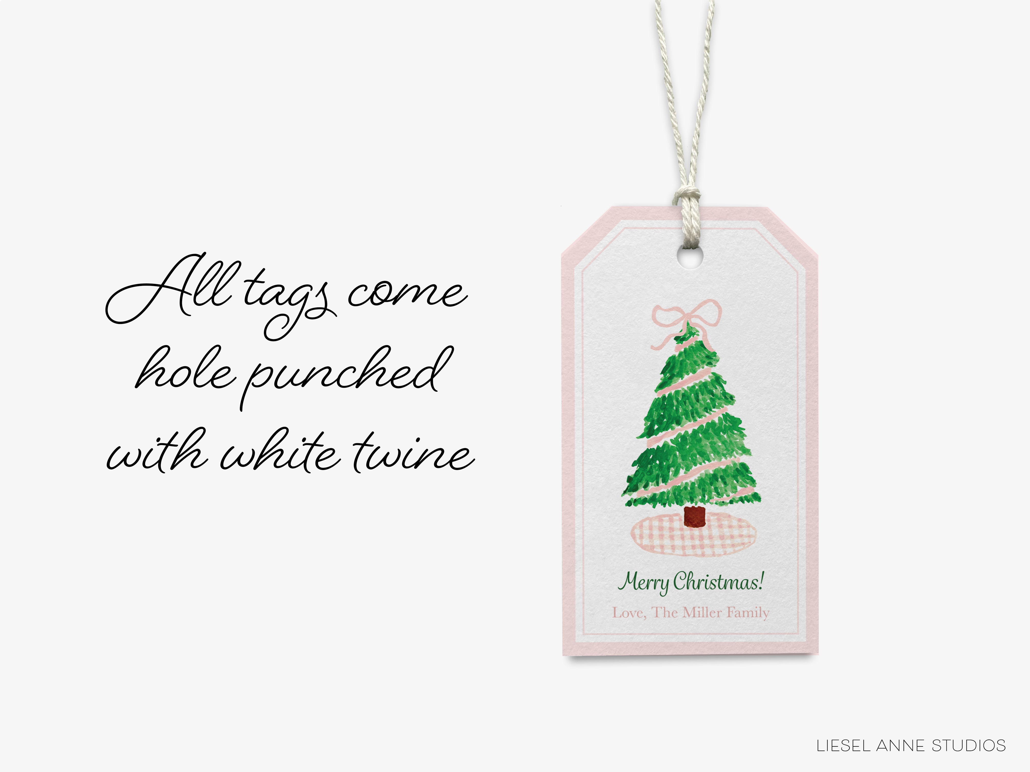 A pink tag with a Christmas tree illustration and text, hanging on a string.