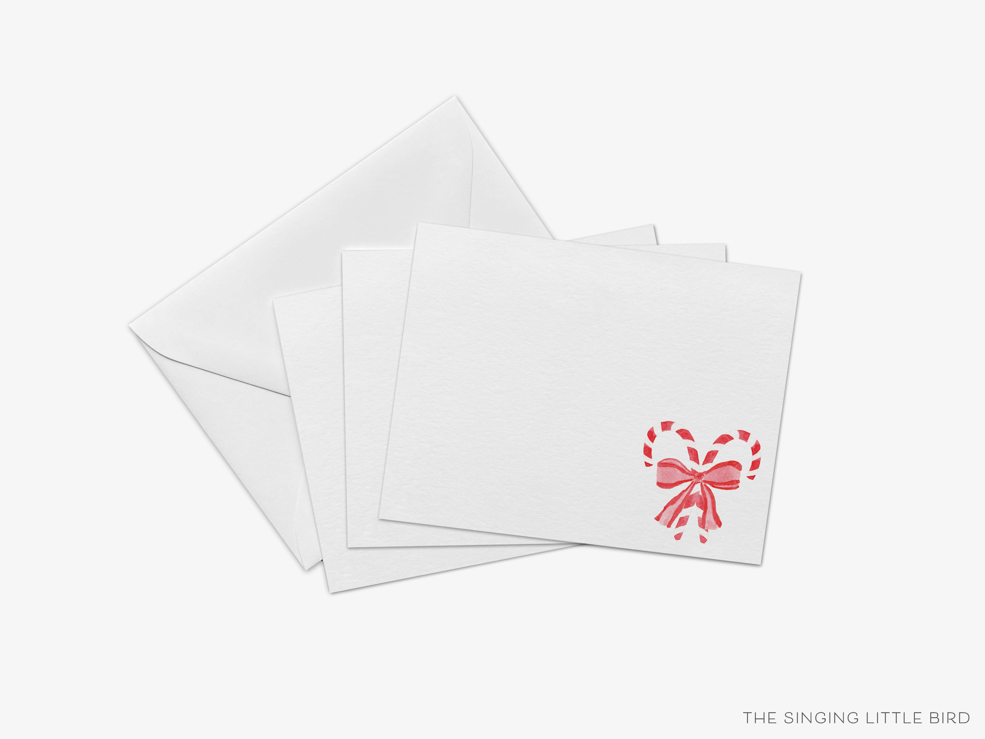 a stack of white greeting cards with a red bow and candy cane design on the right side.
