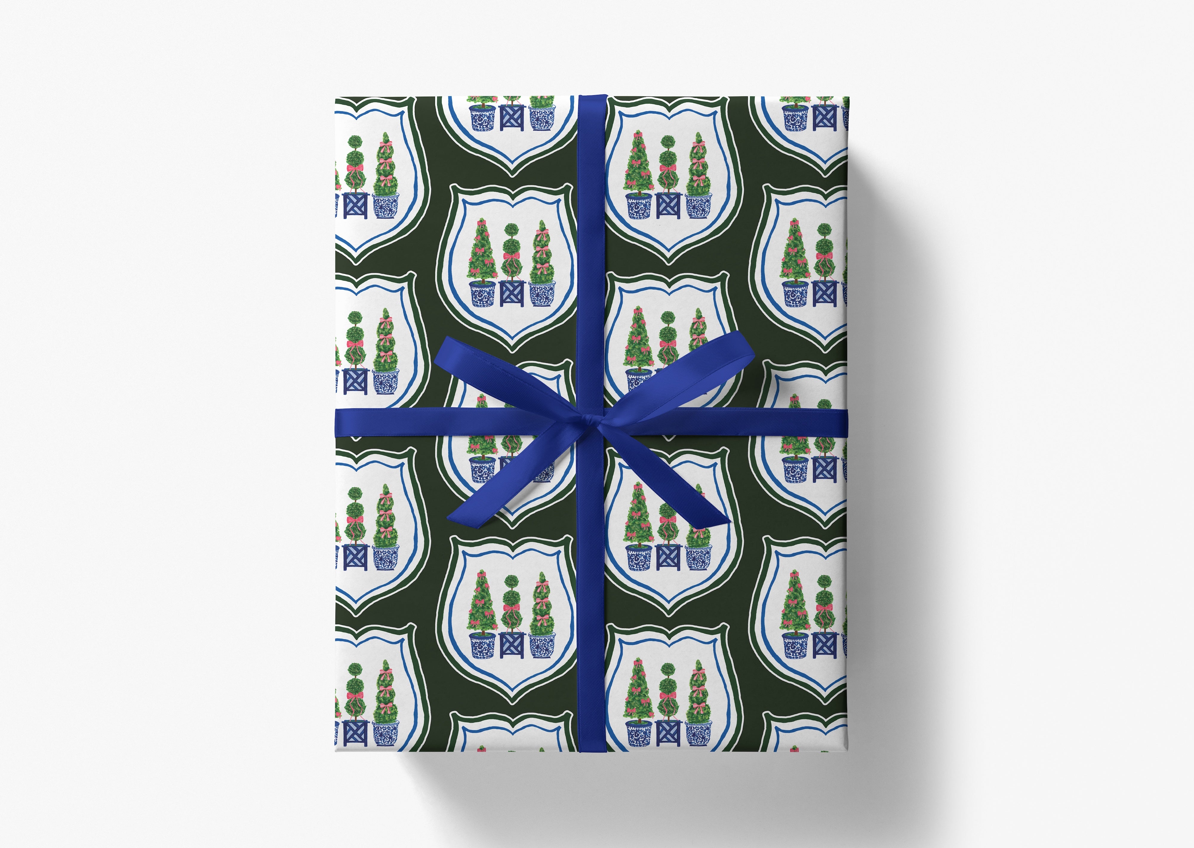 The image is a gift box wrapped in a blue ribbon, featuring a repeating pattern of shield-shaped designs with Christmas trees and ornaments.