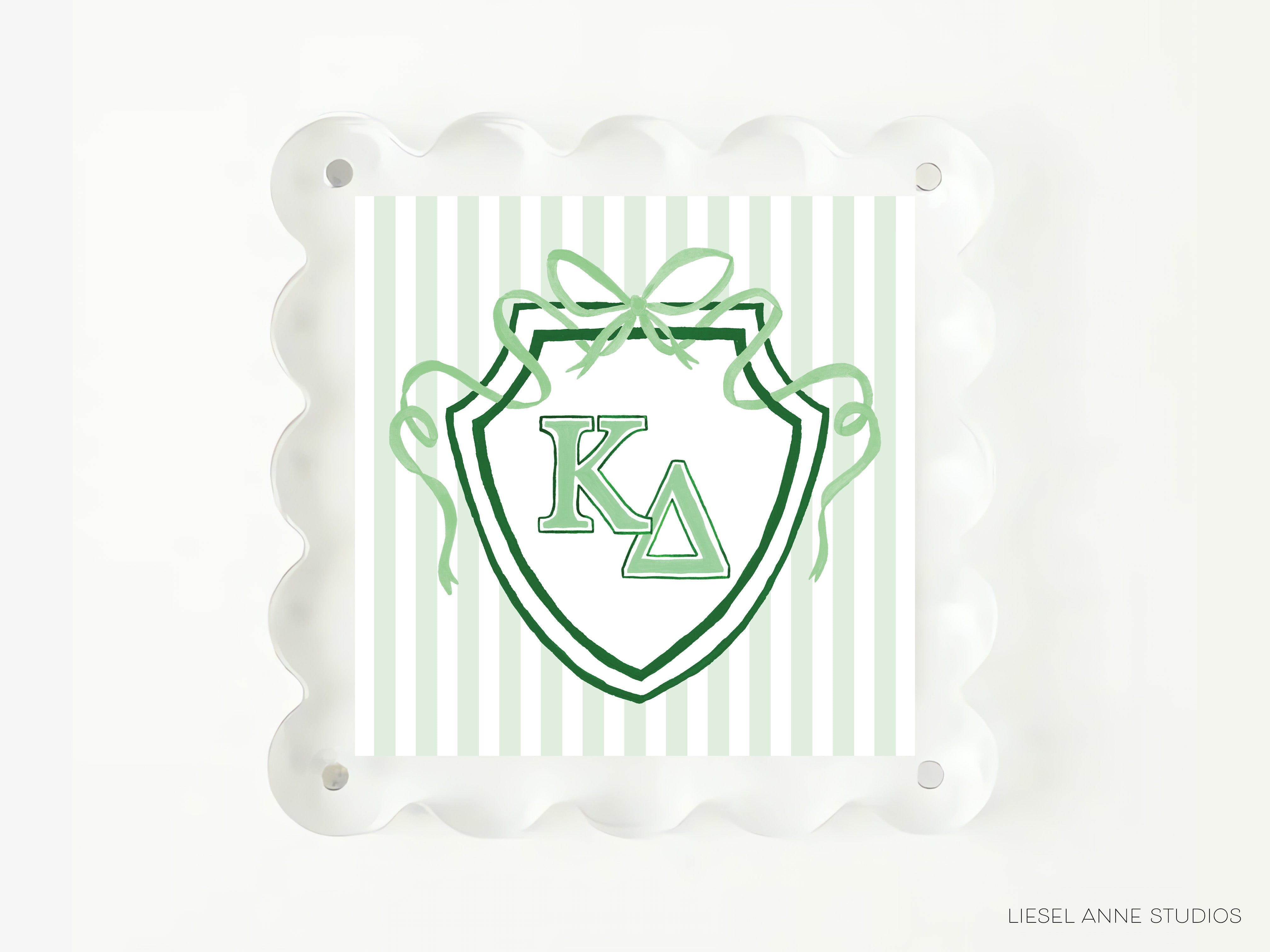 A shield-shaped graphic with the letters 'K' and 'Δ' prominently displayed, surrounded by green ribbons and a bow.