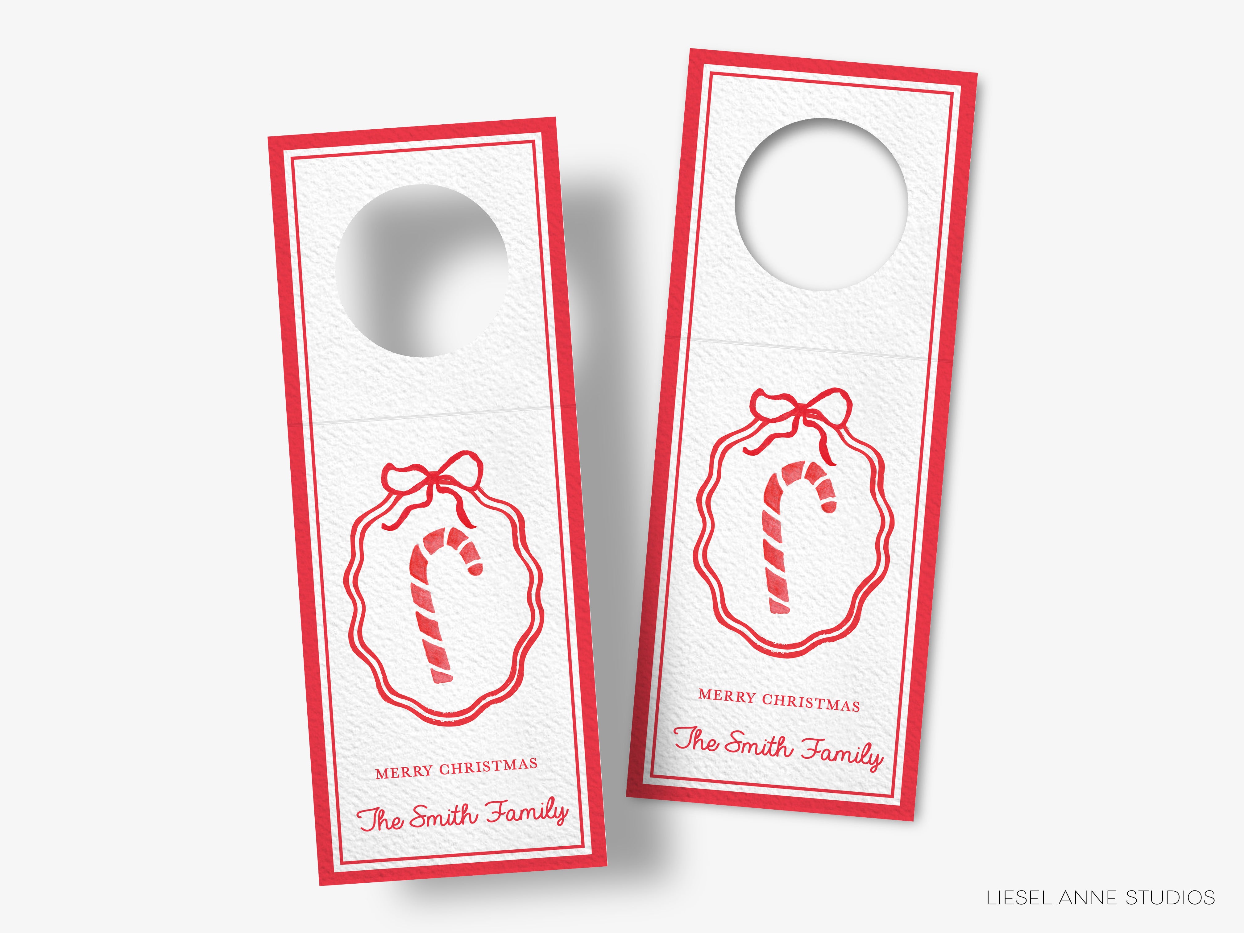 two identical white door tags with red borders and a red ribbon design. The text on the tags reads "Merry Christmas" and "The Smith Family".